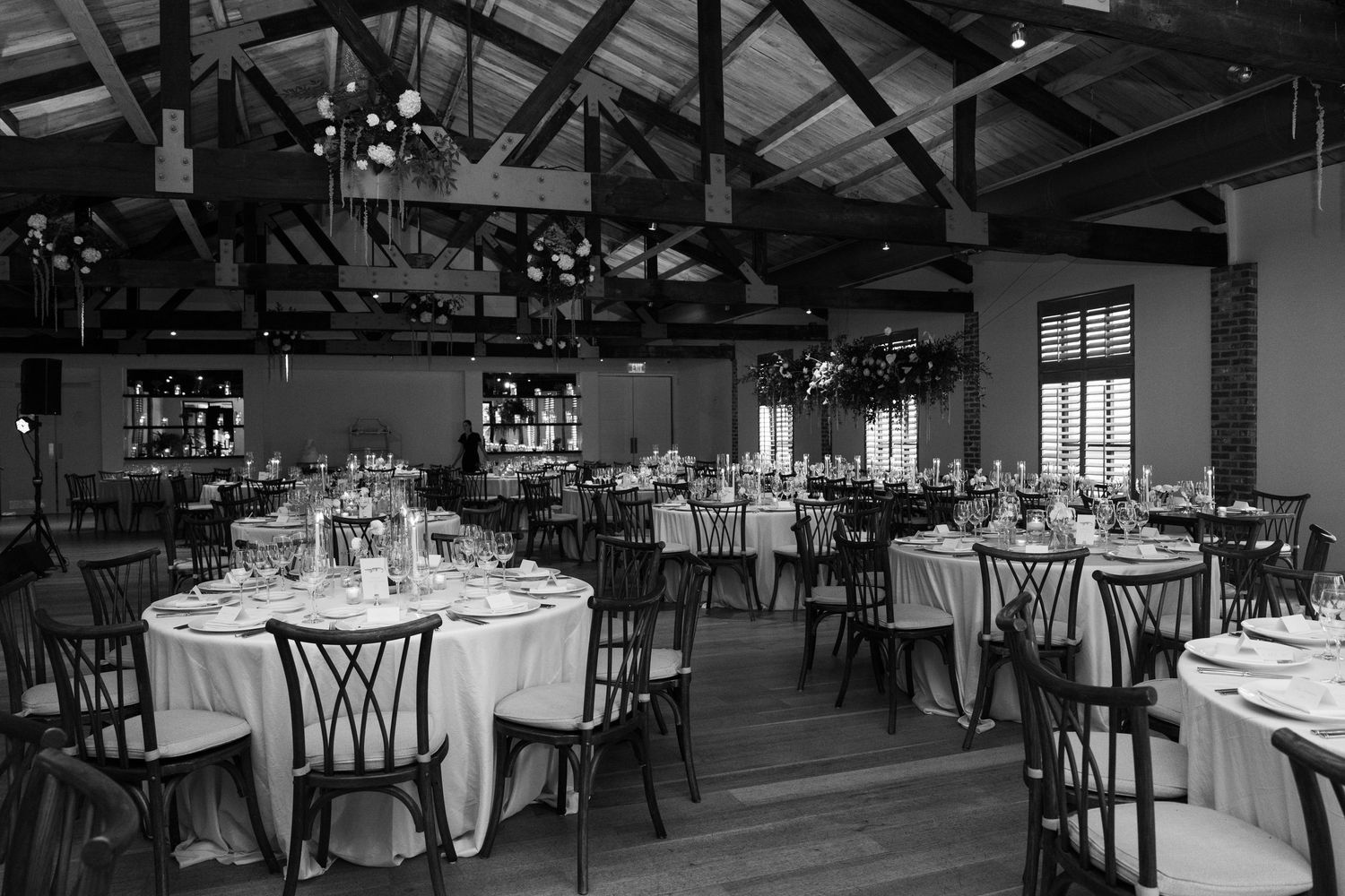 Panoramic view of a dark, elegantly set banquet hall with exposed wooden beams.