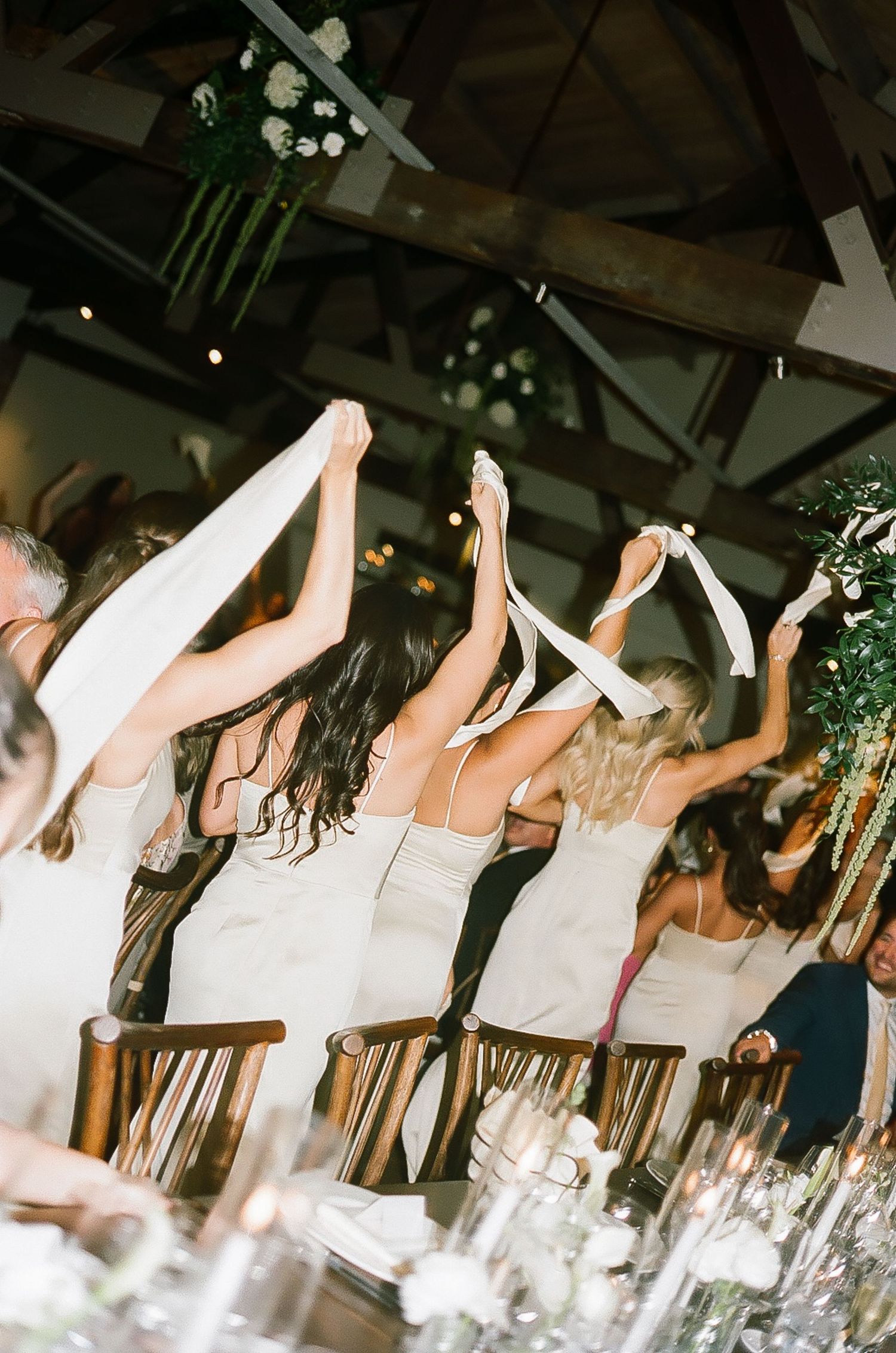 Wedding guests raise their hands in celebration during a festive reception.