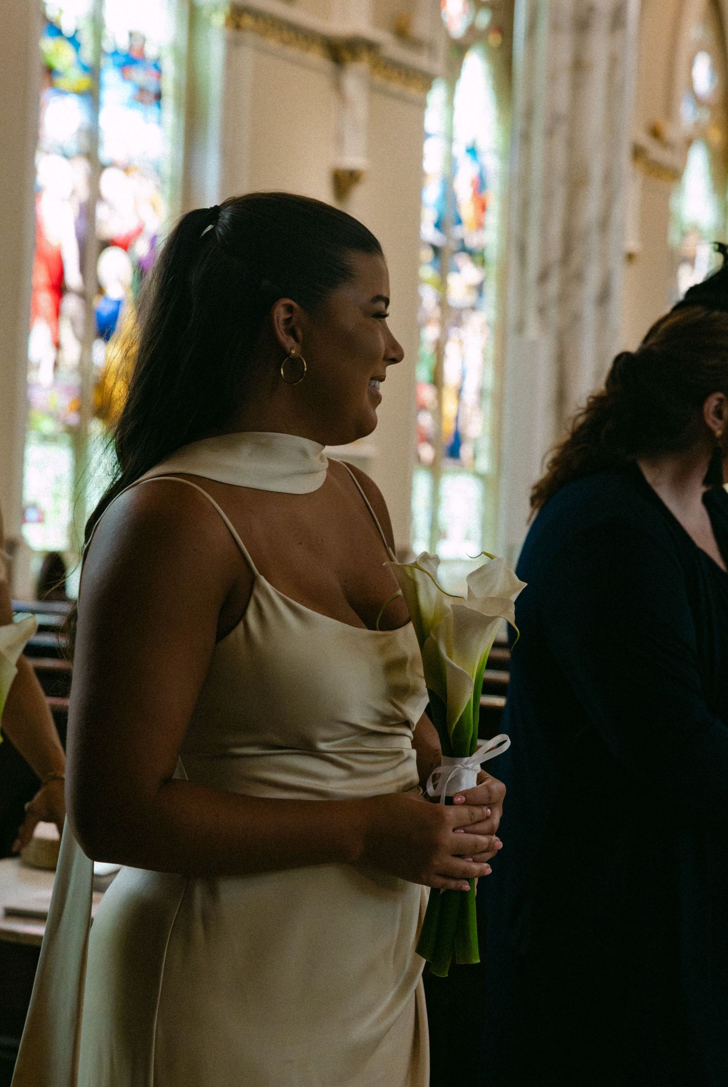 Wedding party members gather in casual conversation inside an ornate church setting.
