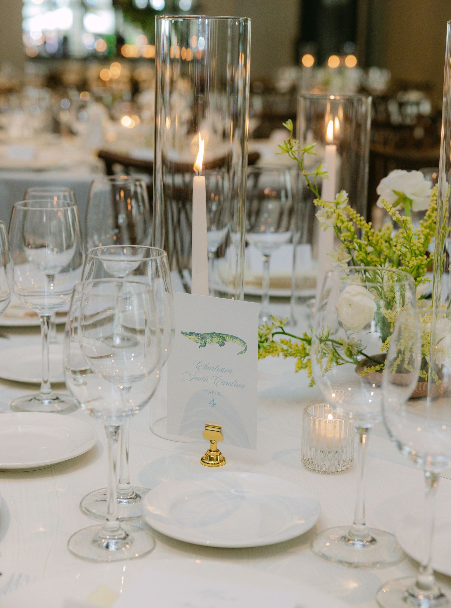 White table settings with wine glasses, candles, and delicate floral accents.