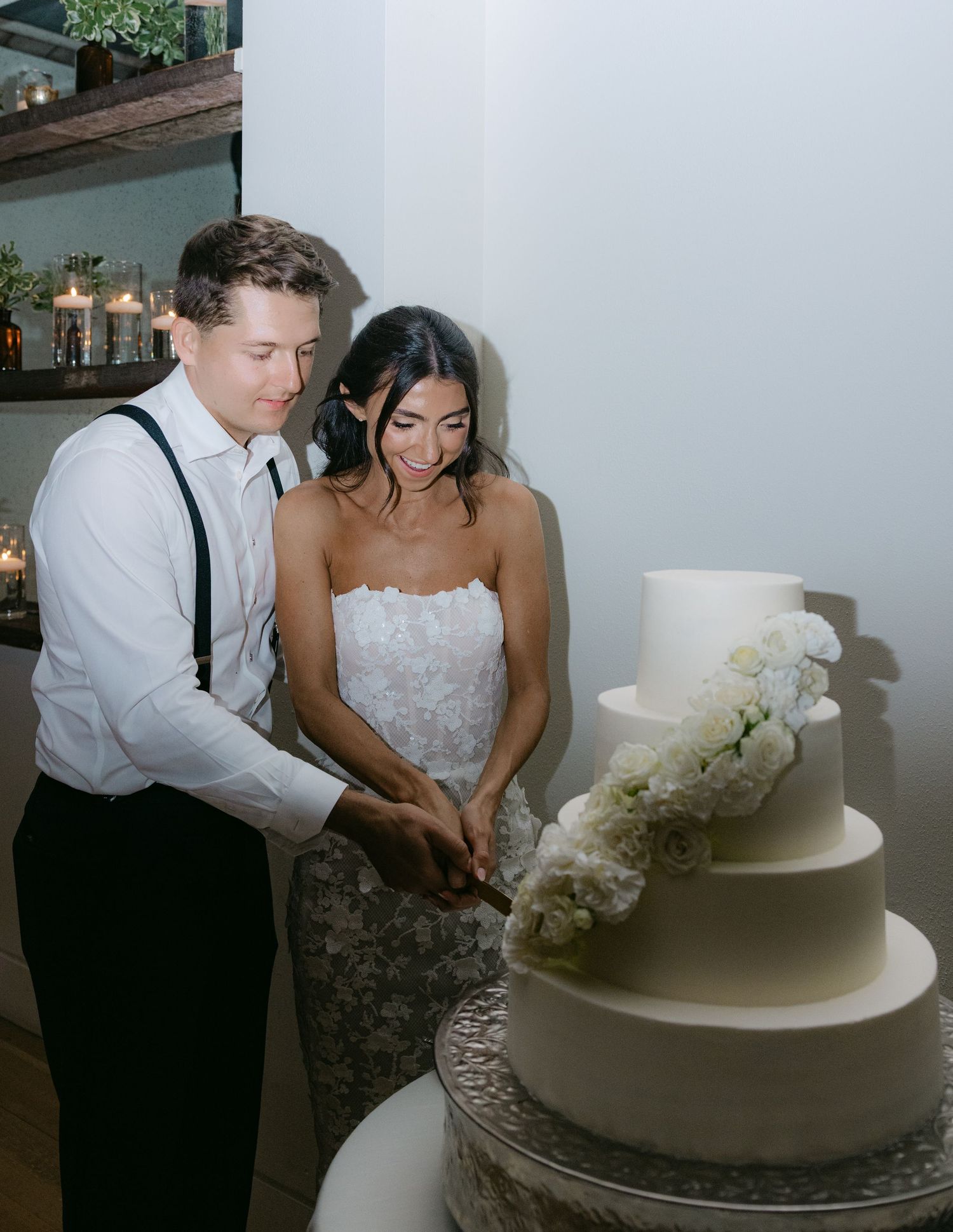 Couple cutting into an elegant white wedding cake adorned with orchids.