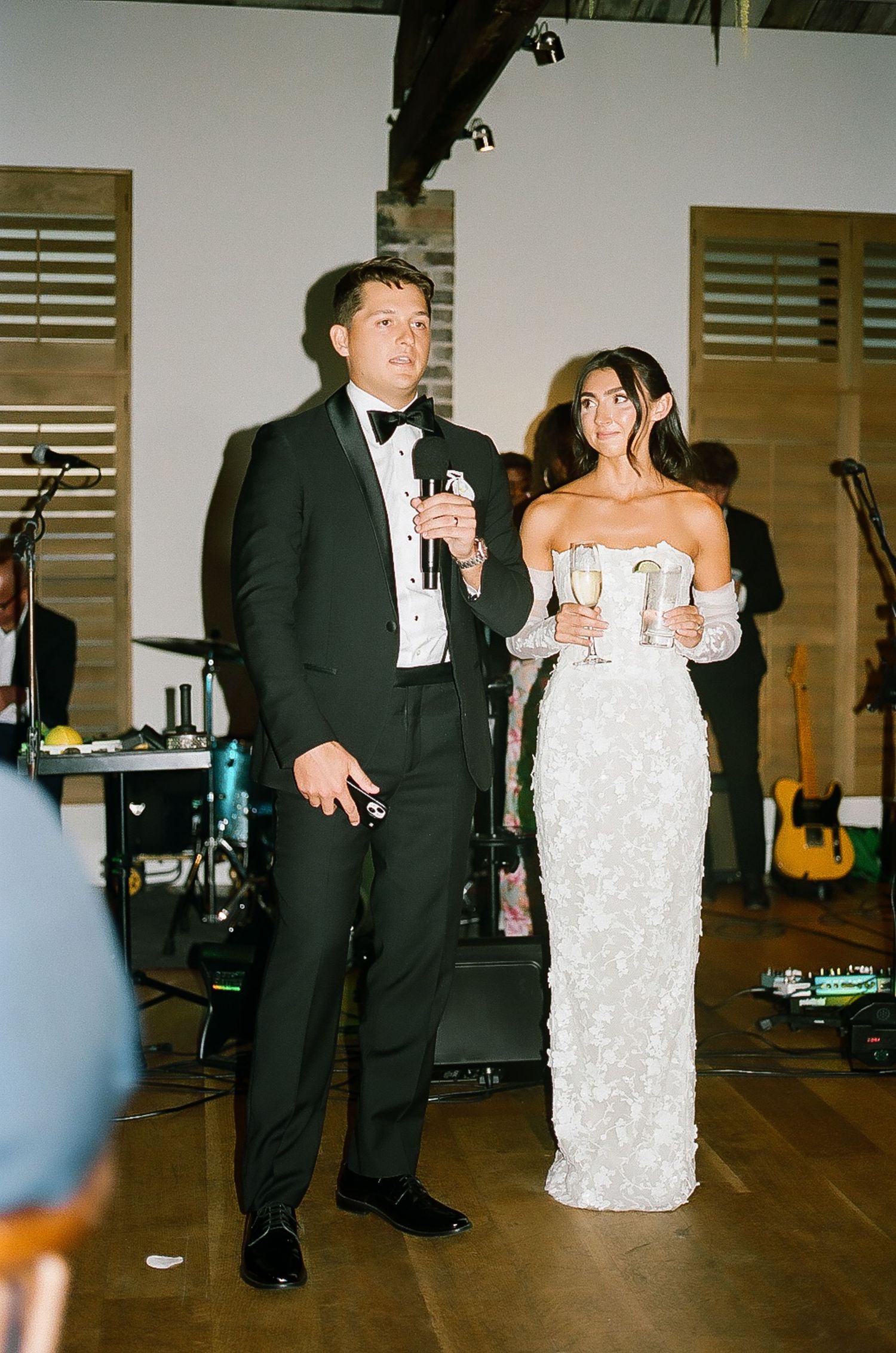 Wedding celebration on a wooden dance floor with live band equipment visible.