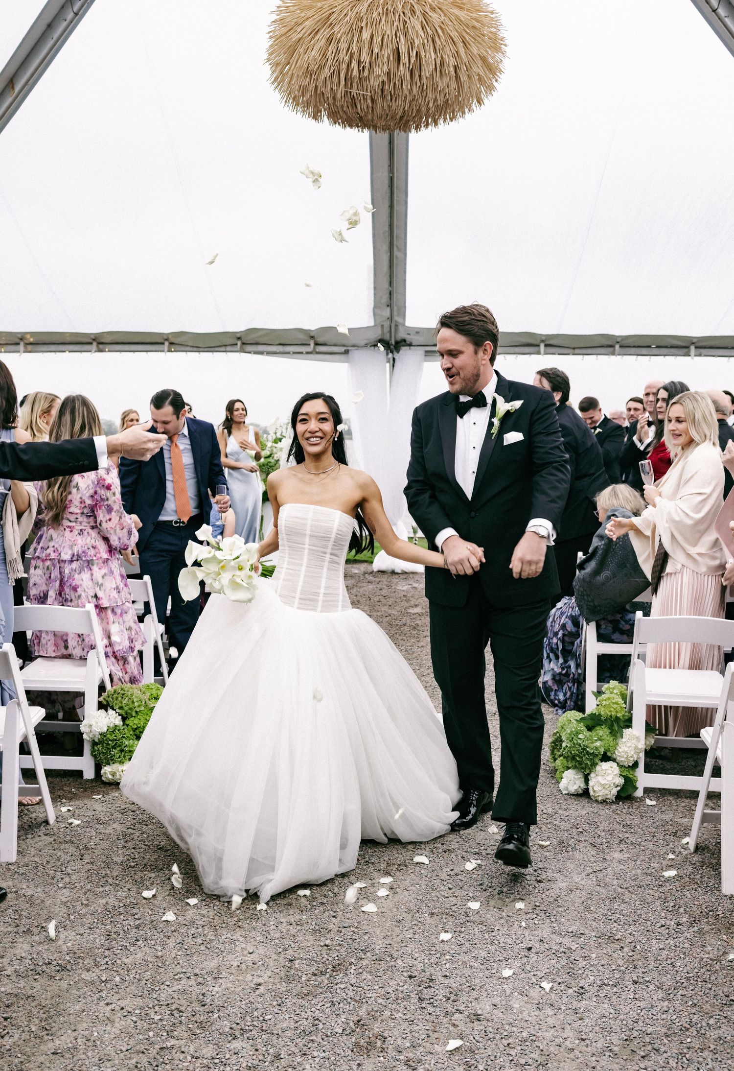 Bride in strapless corset gown and groom in tuxedo walk back down aisle after ceremony.