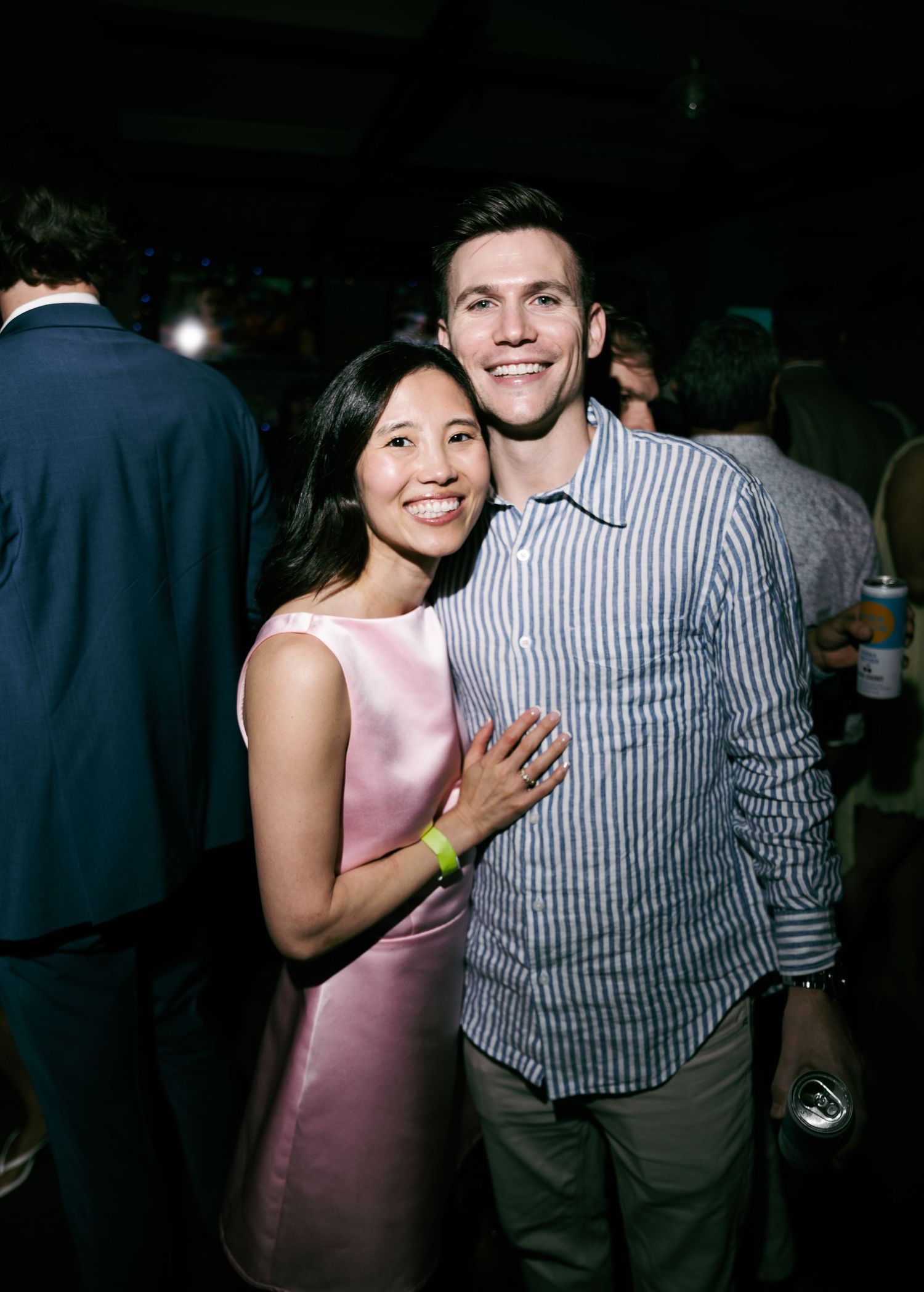 Couple smiling and embracing at an evening social event, woman in pink dress.