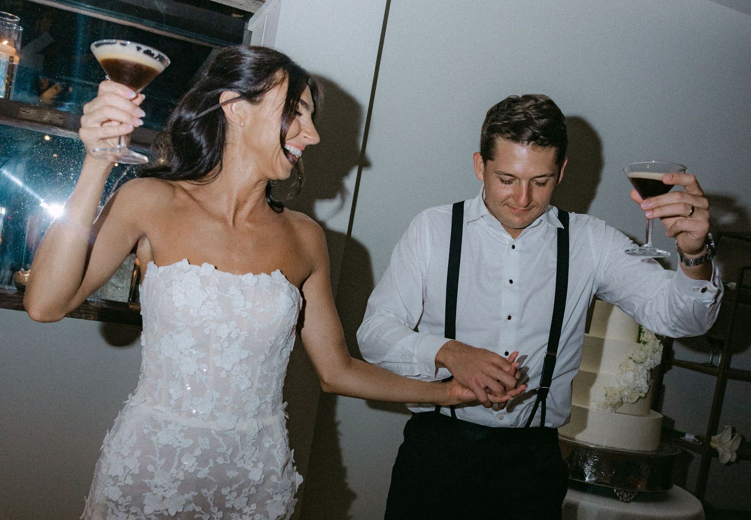 Wedding couple sharing celebratory drinks and laughter at their reception.