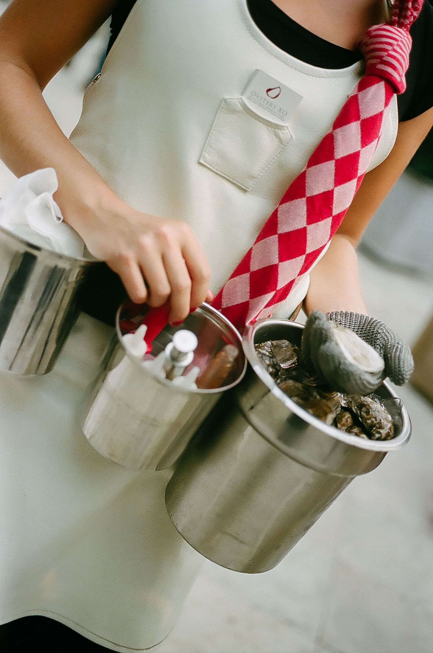 Hands preparing food ingredients using metal kitchen equipment and checkered cloth.
