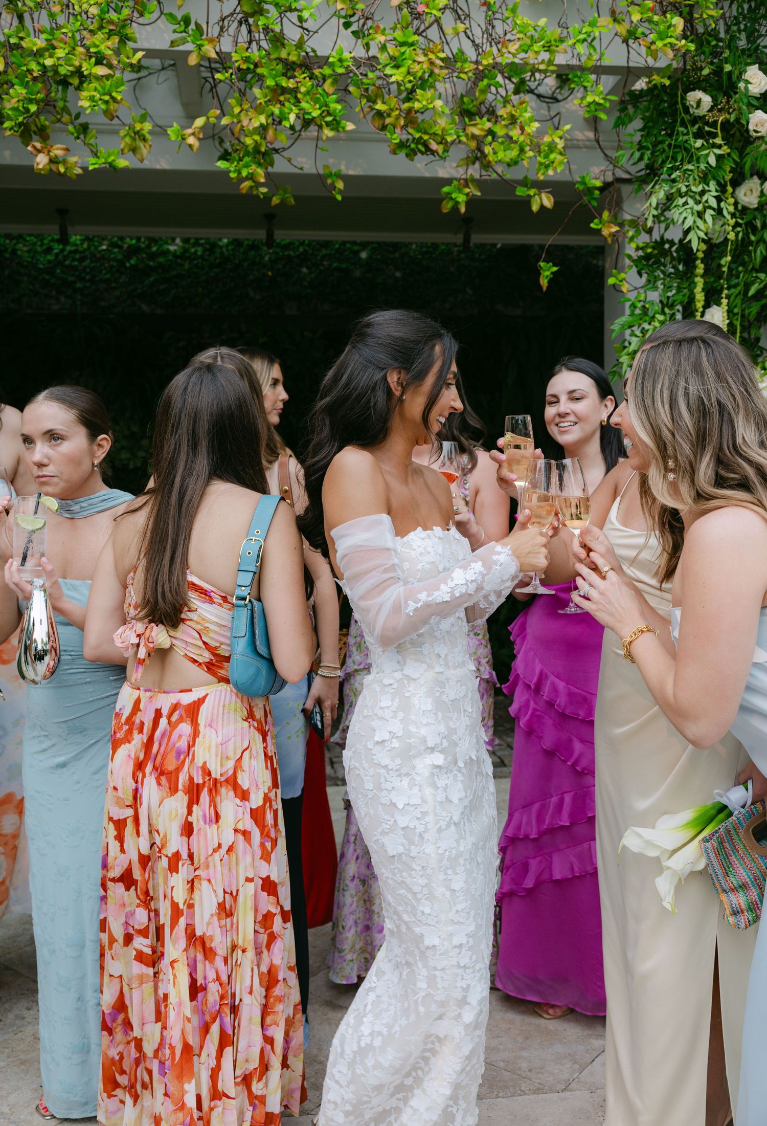 A celebratory group in mixed formal attire shares a festive moment under garden greenery.