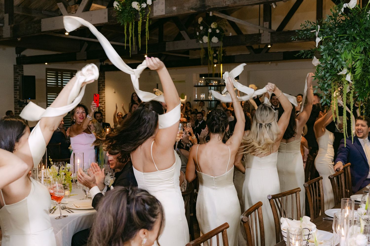 Wedding guests dance and celebrate on a dance floor at a reception.