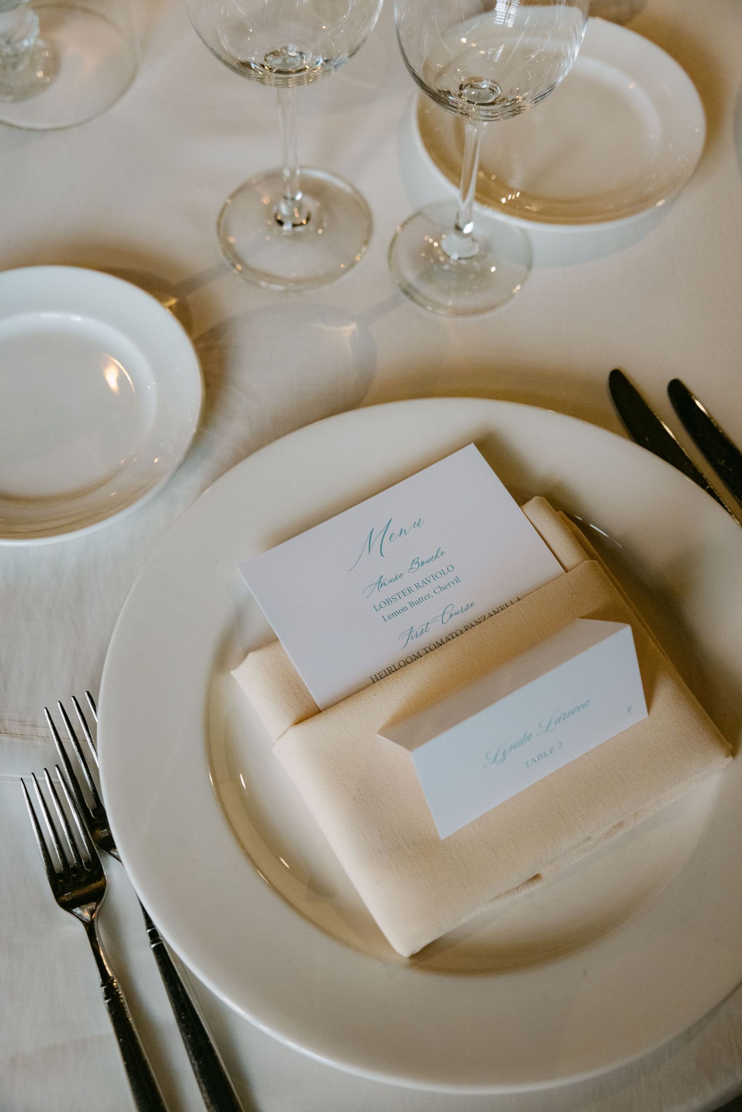 Elegant white place settings with name cards arranged on a formal dining table.