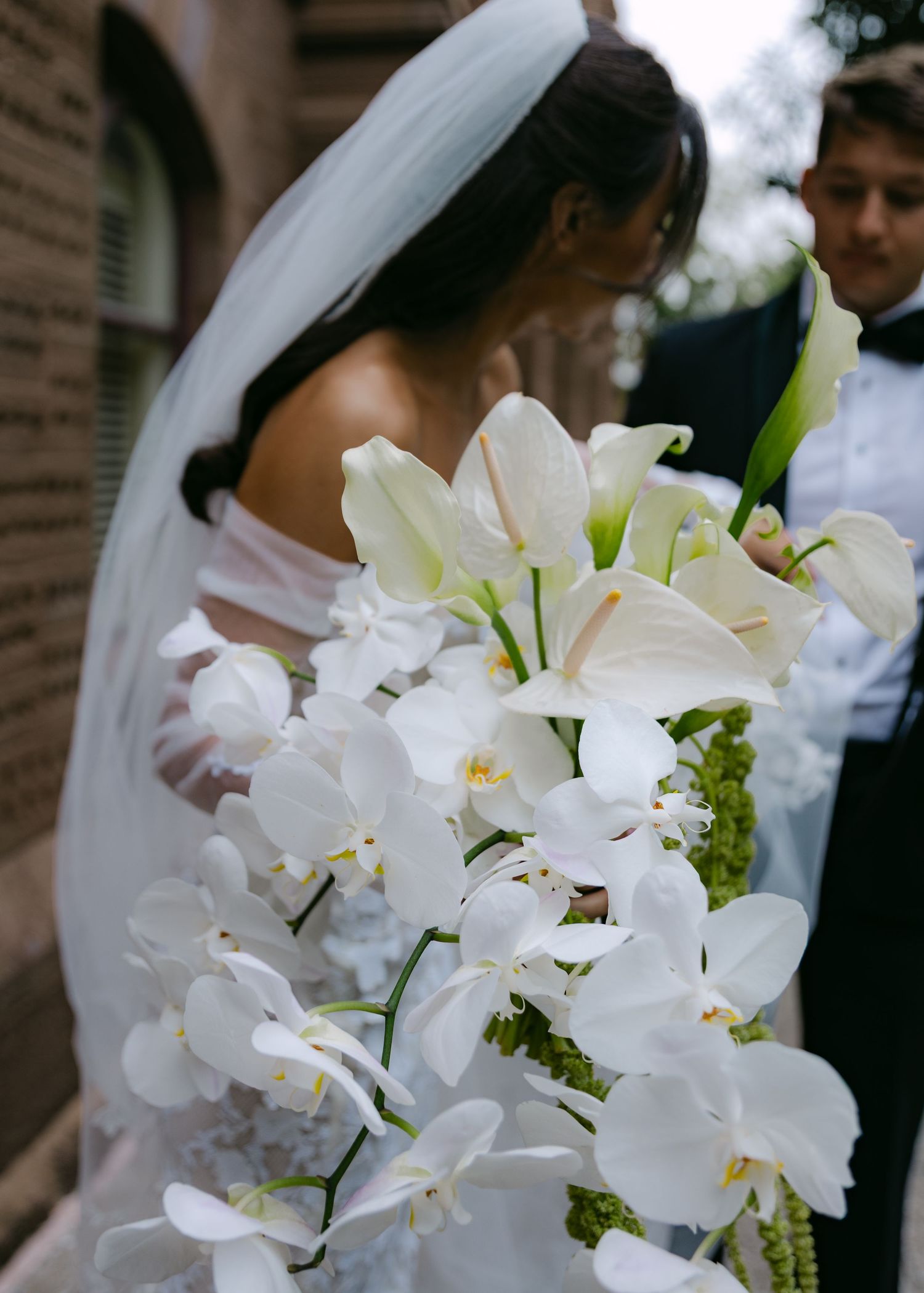 Close-up of white orchid and lily bridal bouquet with cascading flowers.