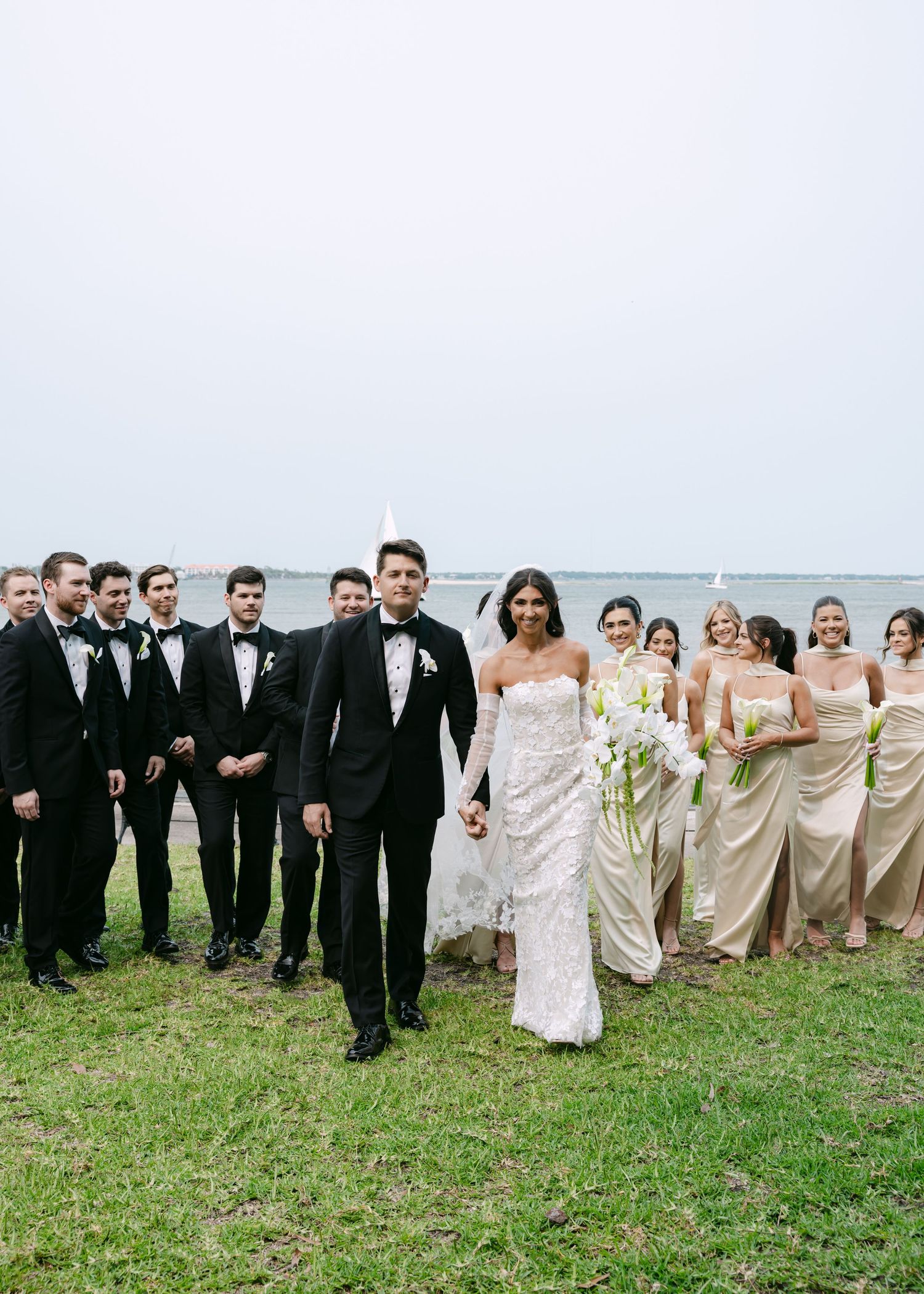 Large wedding party creates a diagonal line formation for outdoor group photo.