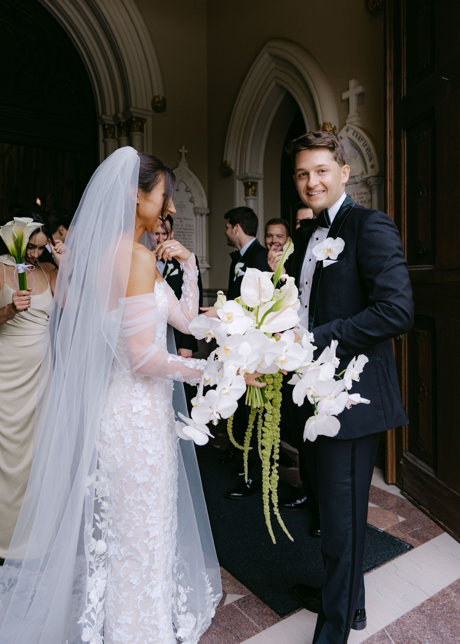 Wedding party candids showing elegant white gown and orchid bouquet in church interior.