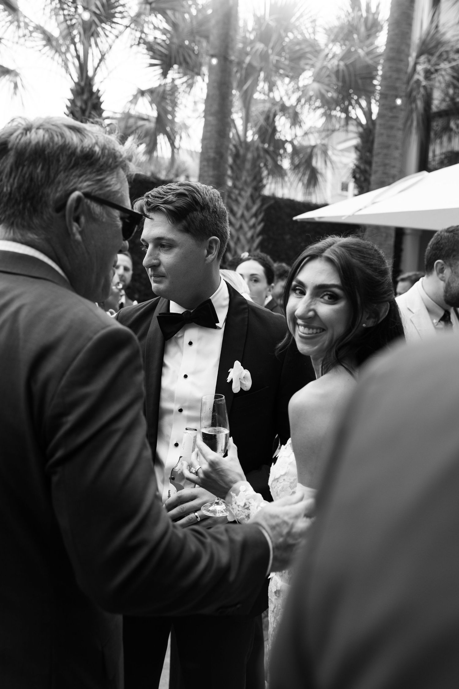 Black and white candid shots of wedding guests interacting at an outdoor celebration.