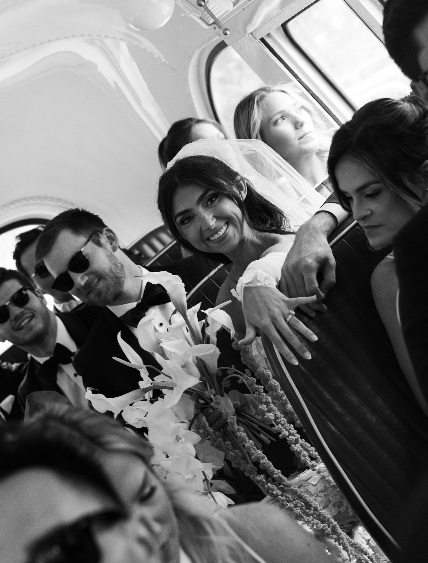 Black and white photo of wedding guests laughing and having fun inside a venue.