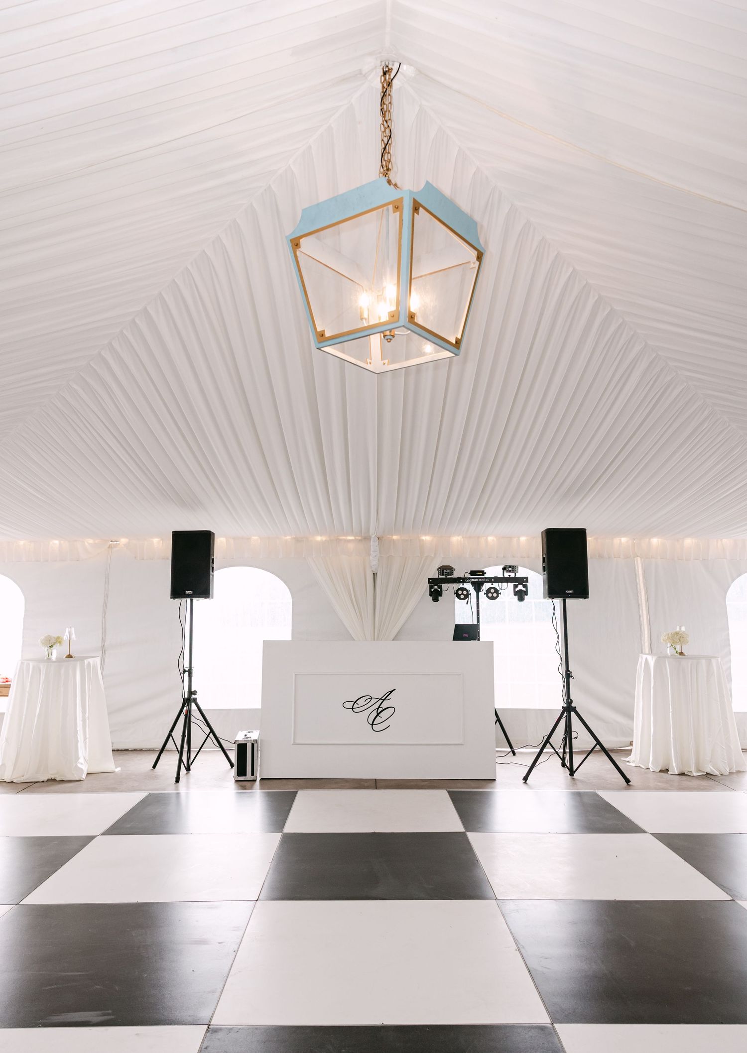 Elegant white wedding tent with black and white checkered dance floor and monogram DJ booth.