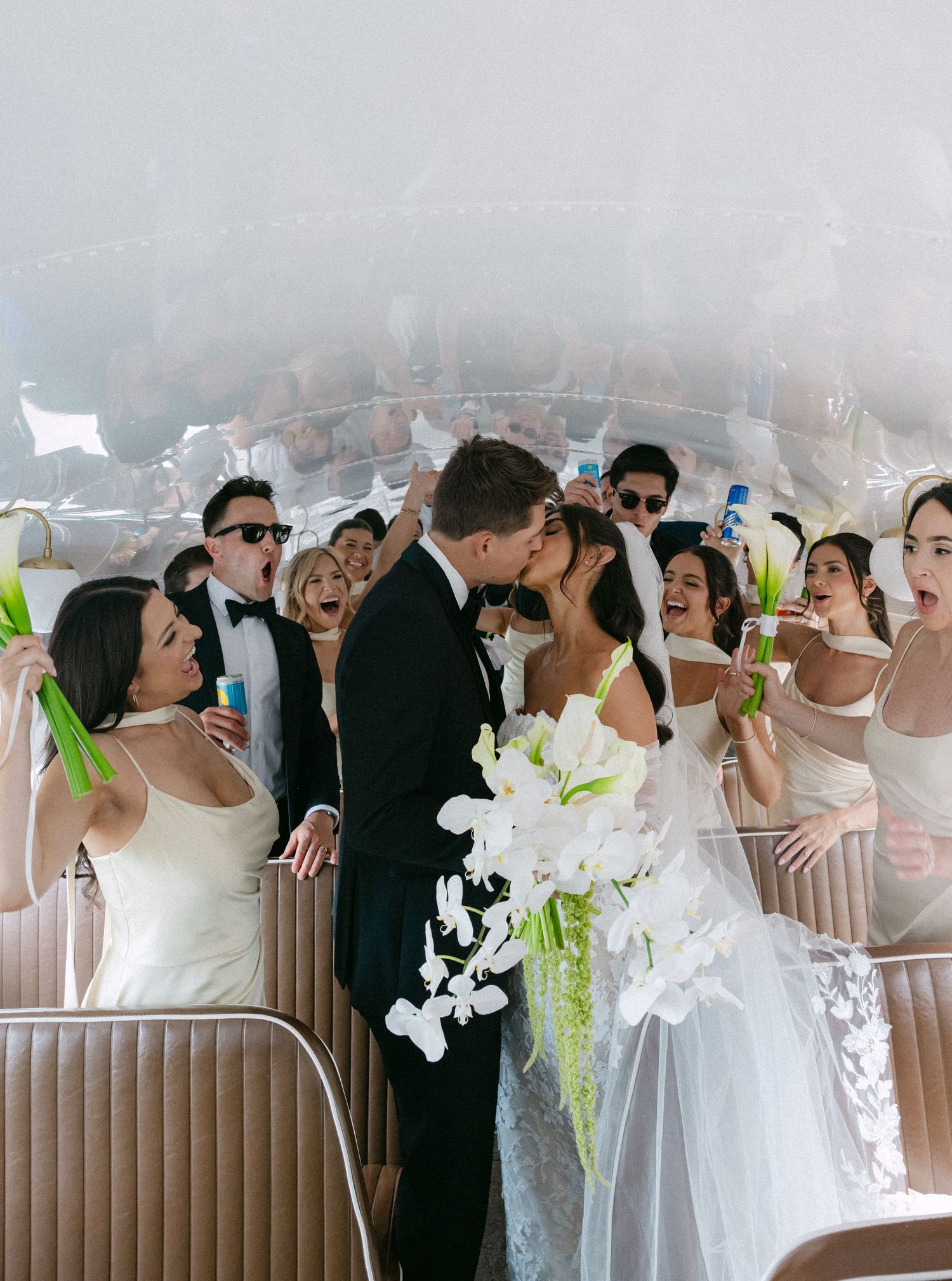 Wedding guests mingle and celebrate in an elegant indoor venue decorated with white orchids and modern furnishings.