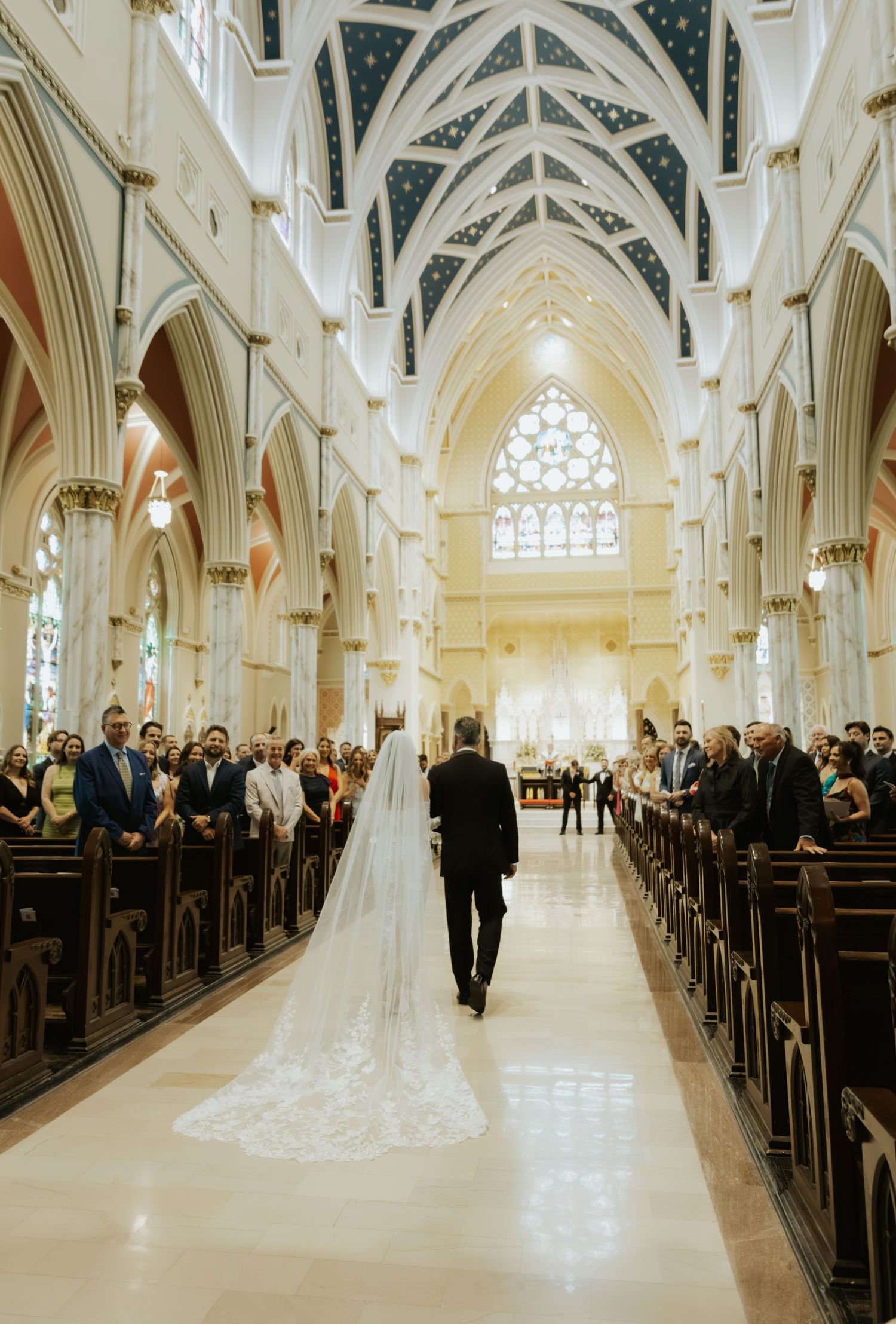 Stunning cathedral wedding ceremony with gothic arches and long aisle filled with guests.