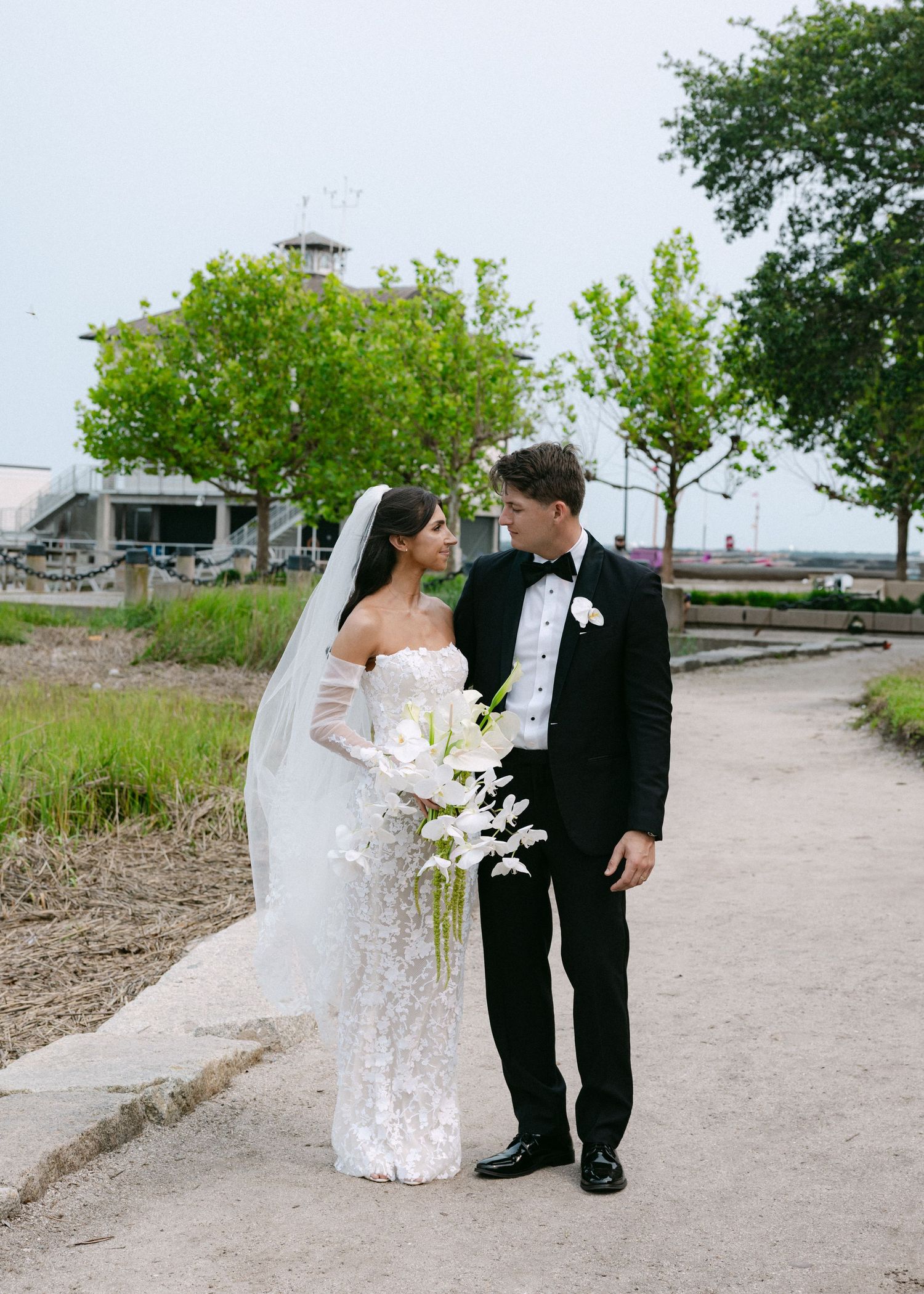 Newlyweds share romantic moments on a rustic outdoor path surrounded by greenery.