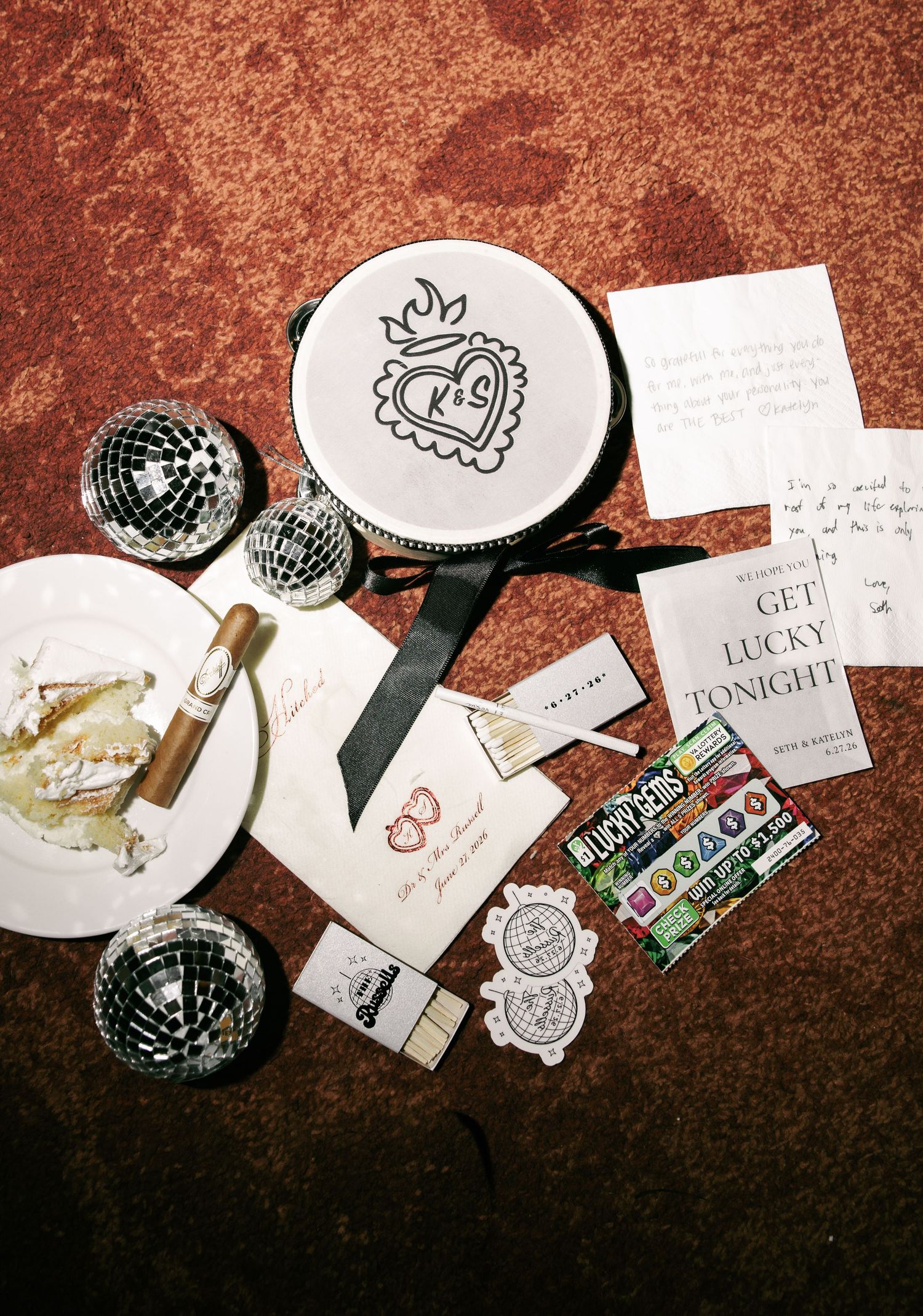 Flat lay of wedding reception party favors including disco balls, cigars, stickers, and custom tambourine.