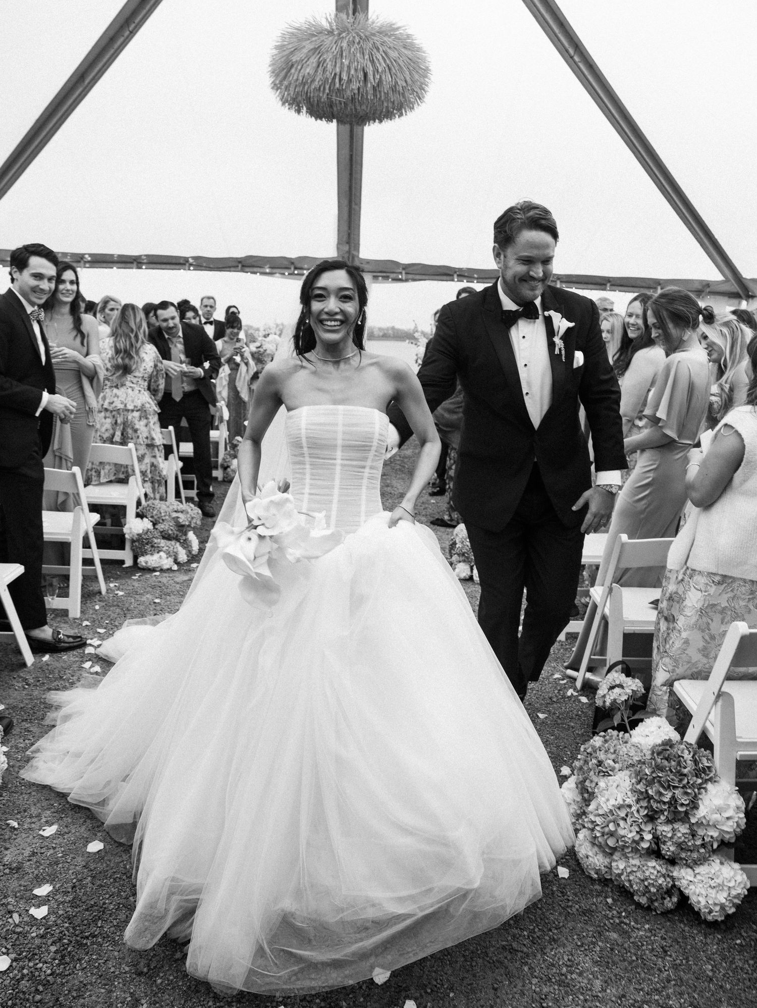 Bride and groom walking down aisle after wedding ceremony in black and white photo.