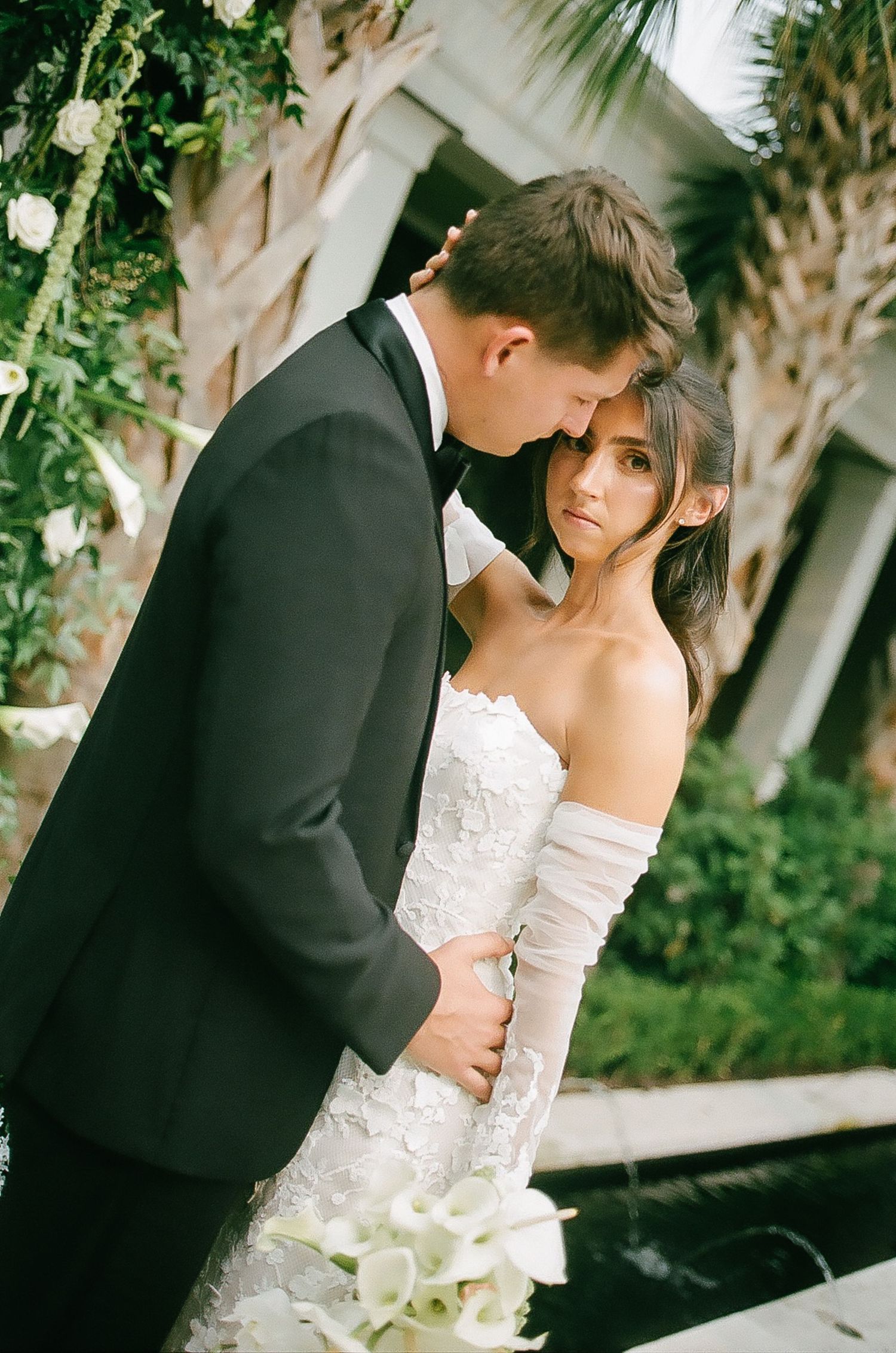 Intimate wedding couple portrait amid lush garden greenery.