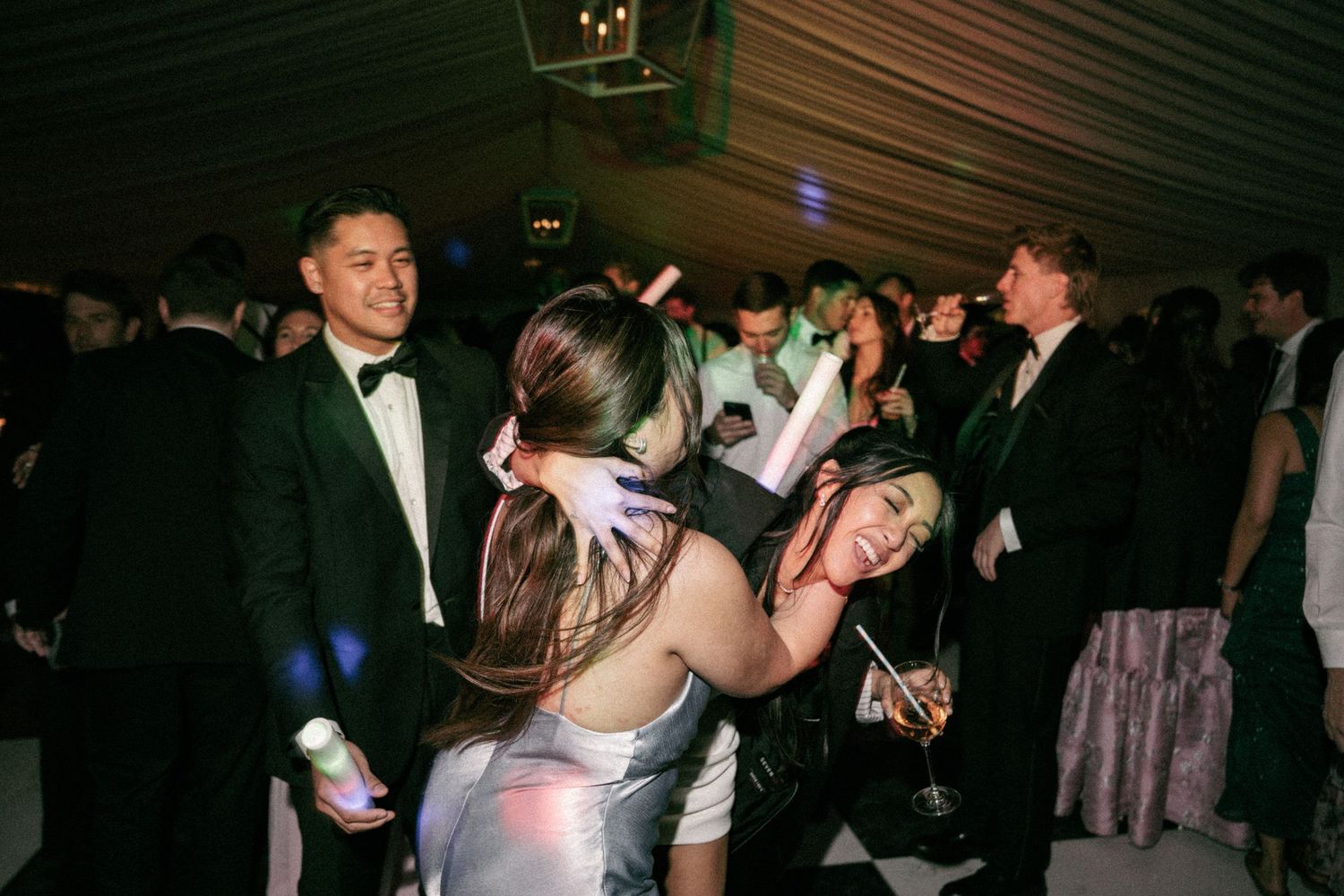 Young adults dancing and socializing at a formal party or prom event in an elegant venue.