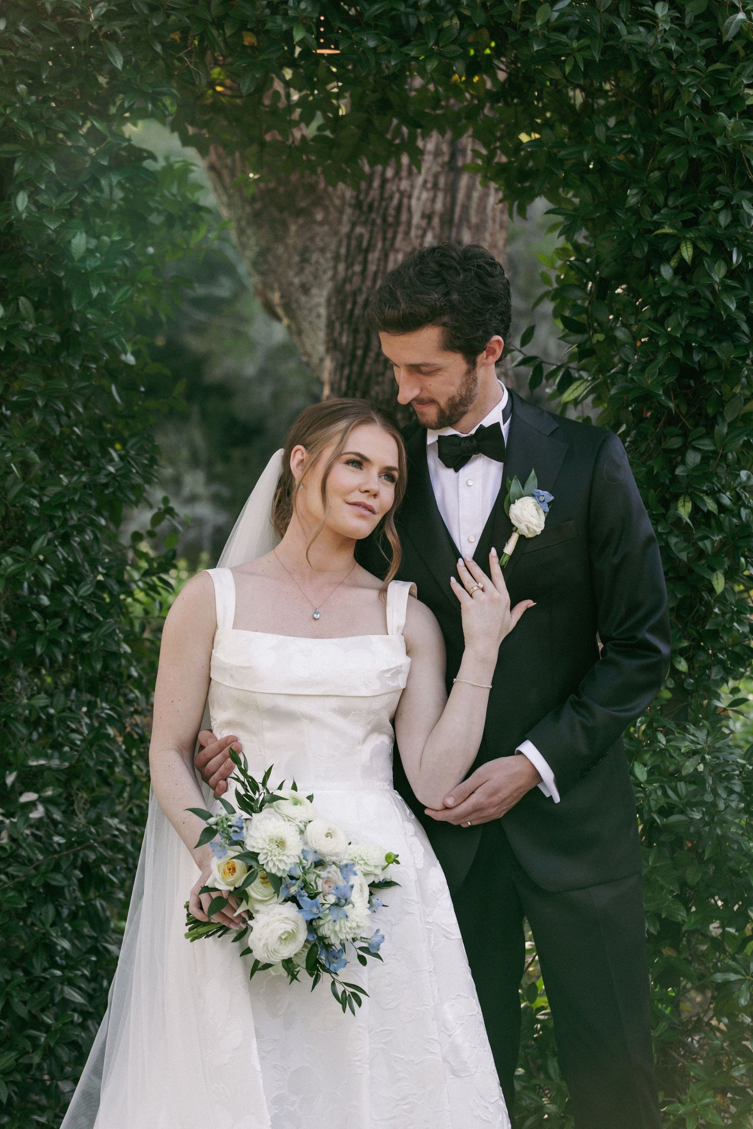 Newlywed couple shares intimate moments in a lush garden setting during their wedding photoshoot.