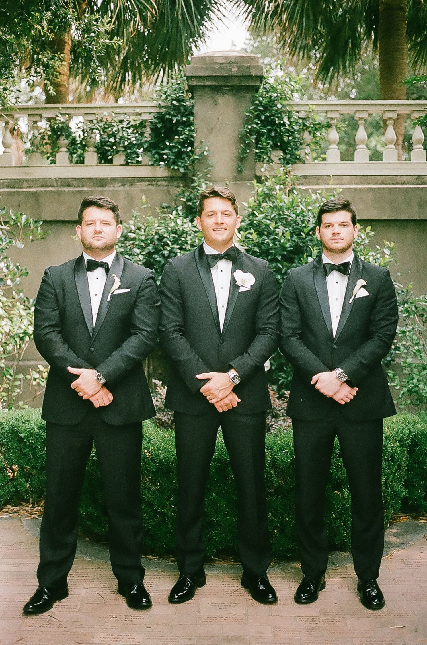 Groomsmen line up wearing matching black tuxedos for formal wedding photos.