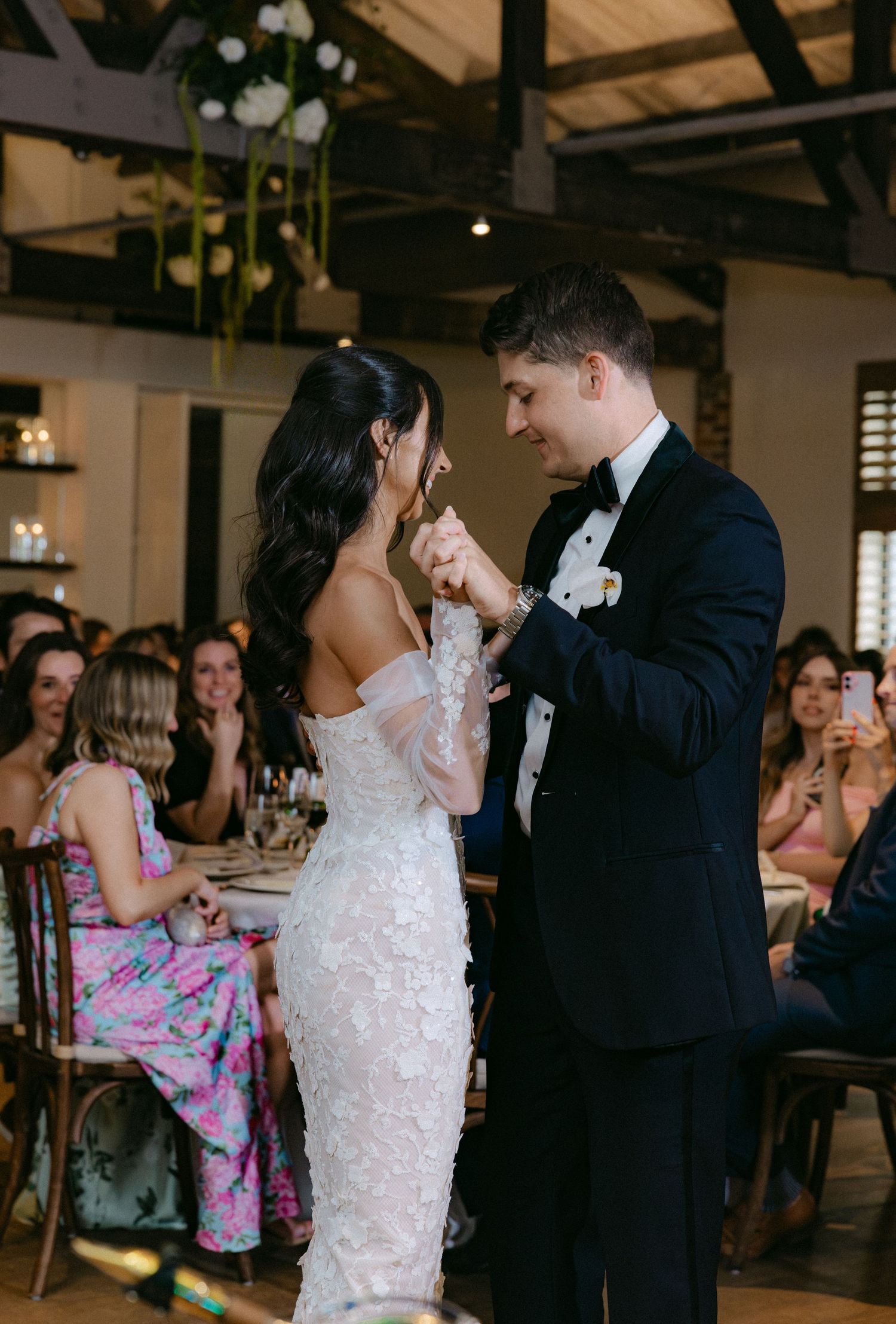 Wedding reception dance floor features couples dancing in elegant venue with wood floors.