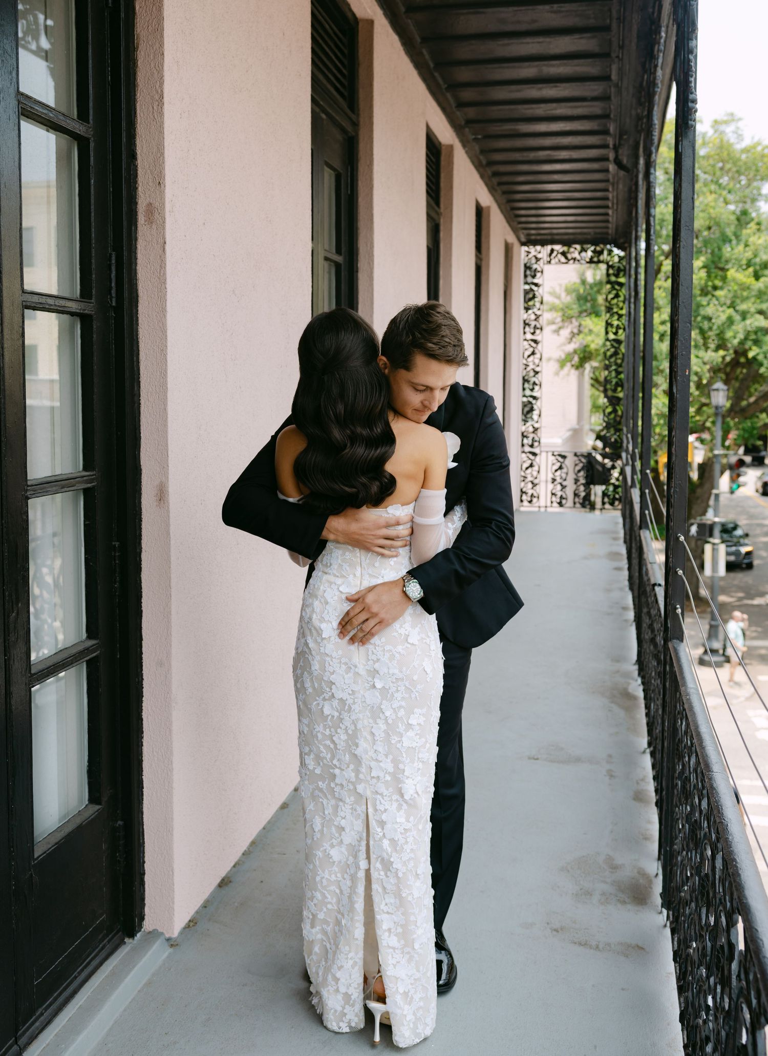 A tender embrace between newlyweds on an elegant covered balcony.