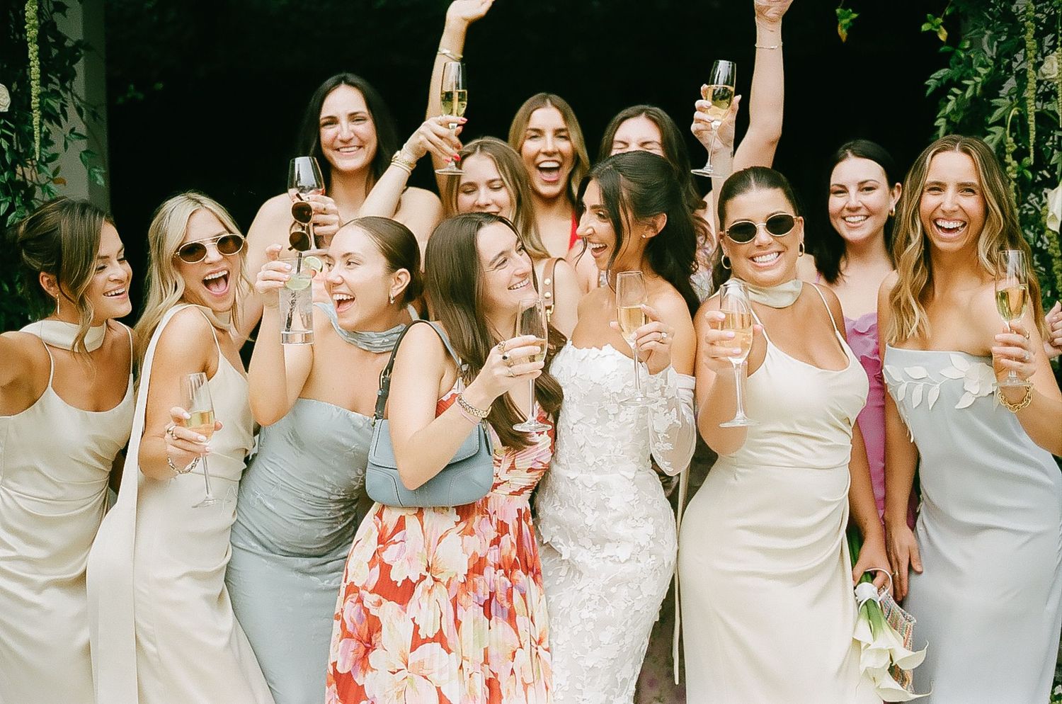 A line of bridesmaids dressed in gray attire celebrating at an outdoor wedding.
