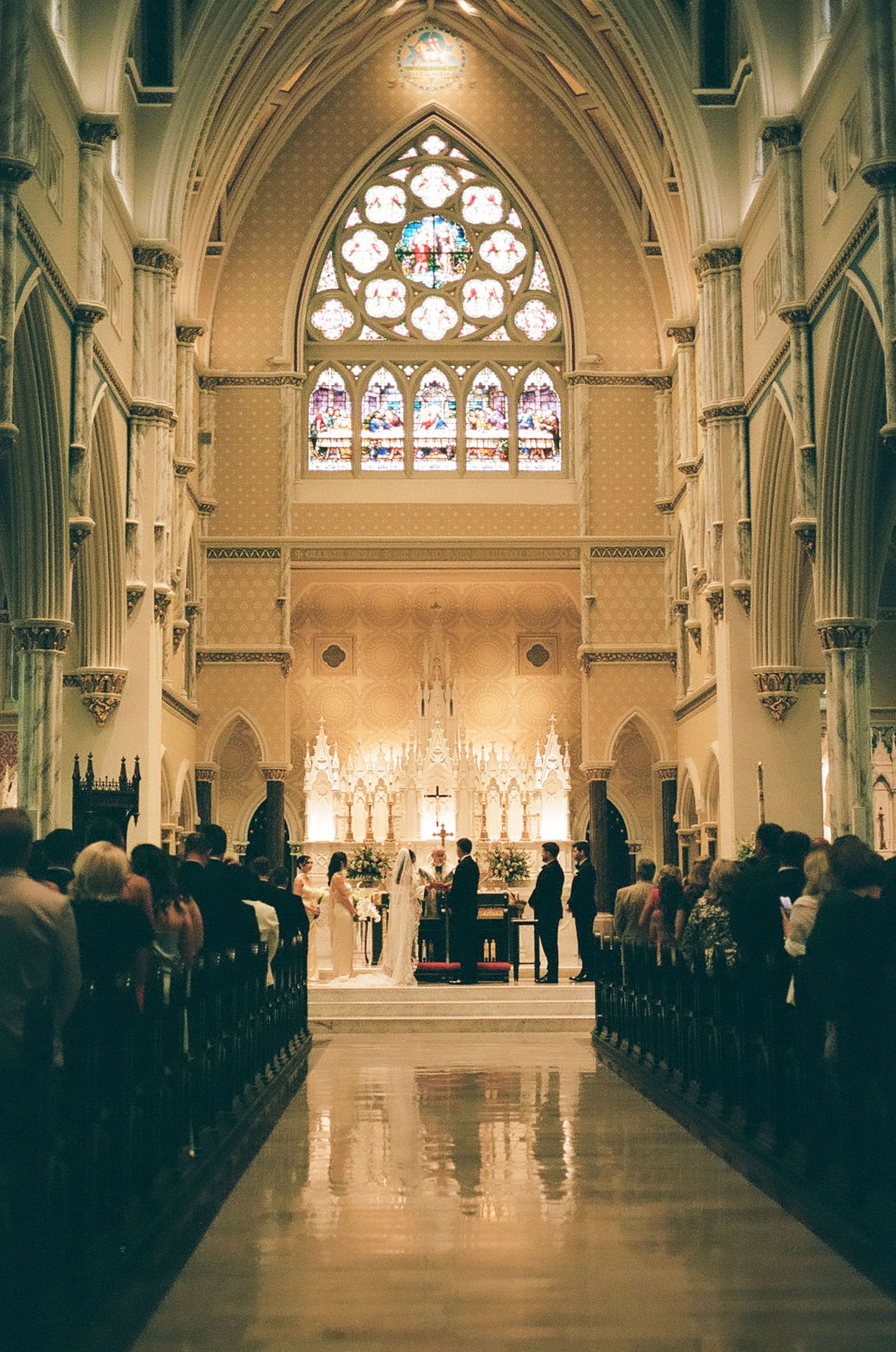 Gothic church interior with vaulted ceilings and stained glass windows during a wedding ceremony.