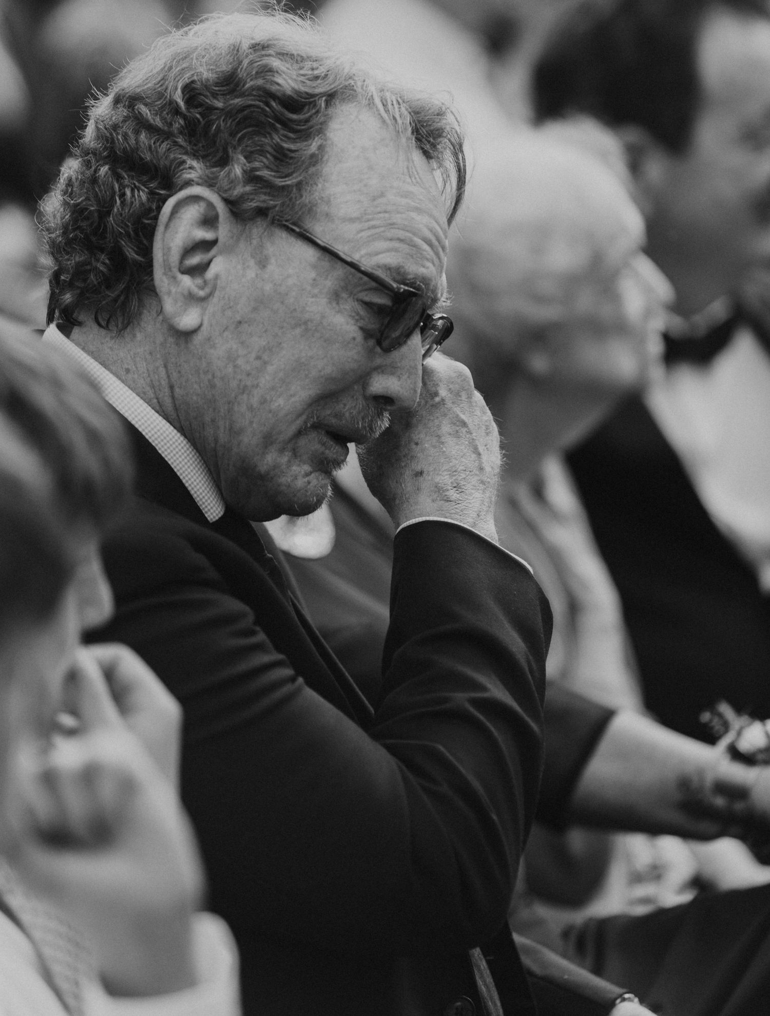 A candid moment captured in black and white showing emotional reactions during a wedding ceremony.