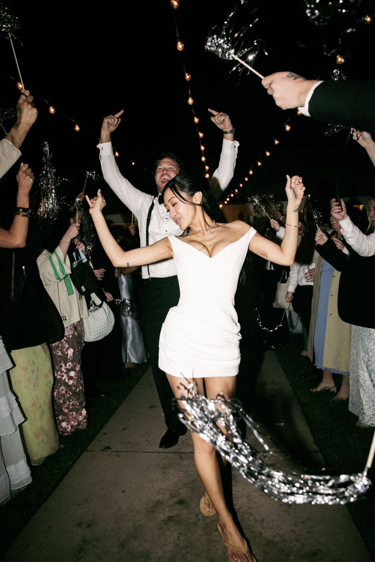 Bride and groom celebrating sparkler send-off exit at outdoor evening wedding reception.