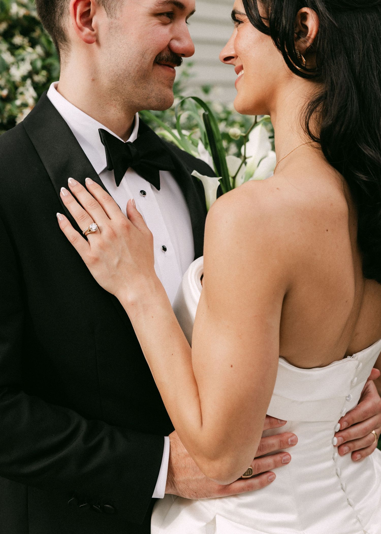 Bride and groom sharing an intimate moment, bride wearing strapless gown with diamond ring visible on her hand.