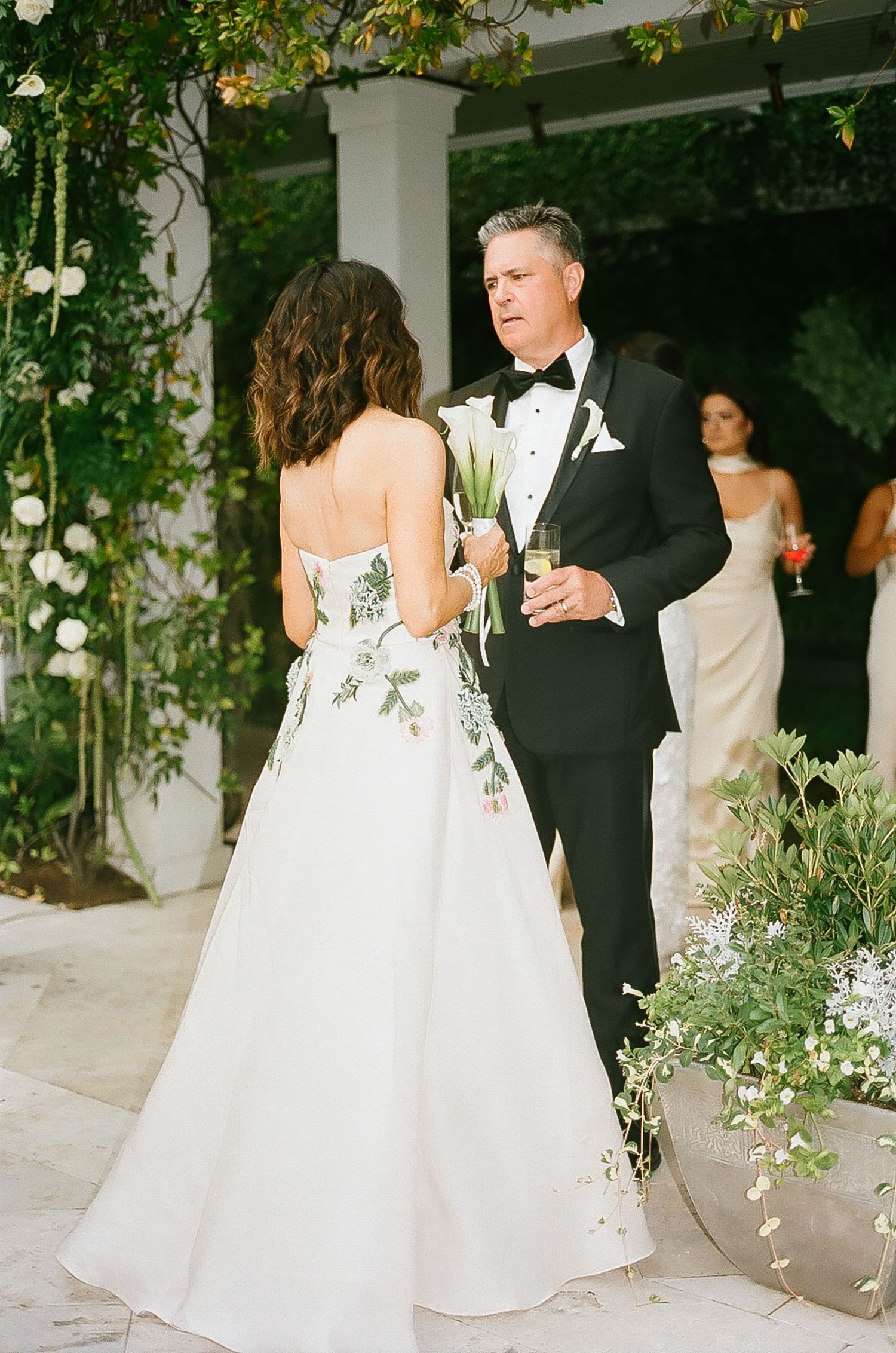 Couples dance at an elegant outdoor wedding reception decorated with floral arrangements.