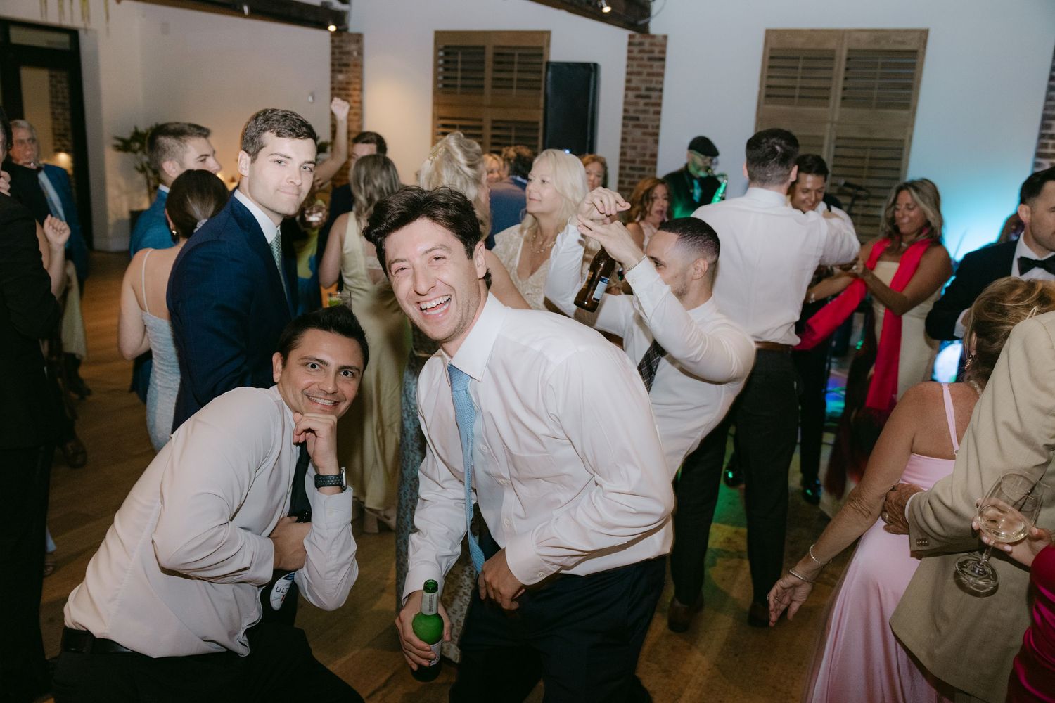 Wedding guests laughing and dancing at a lively reception celebration.