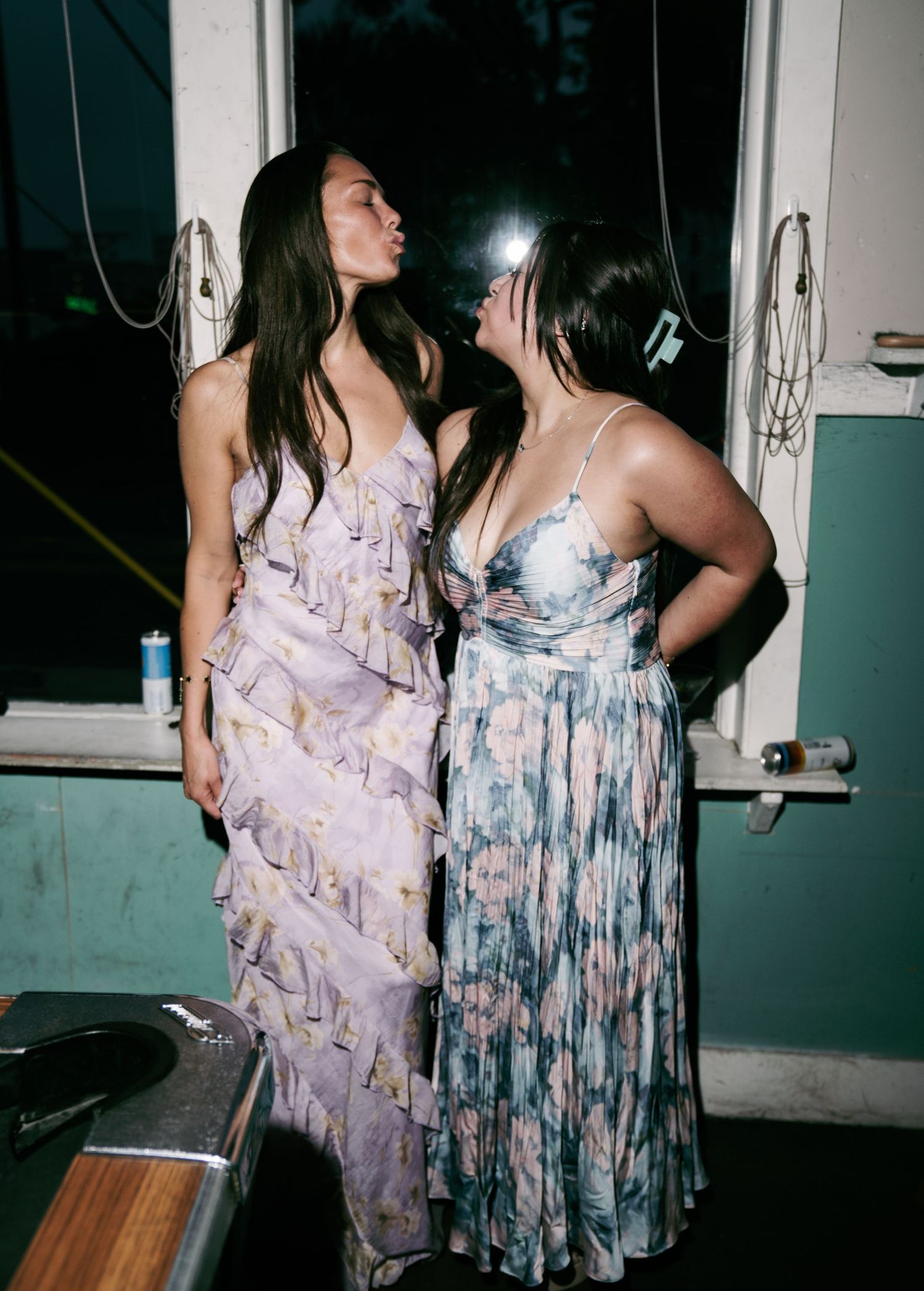 Two women in elegant floral maxi dresses posing together at a party.