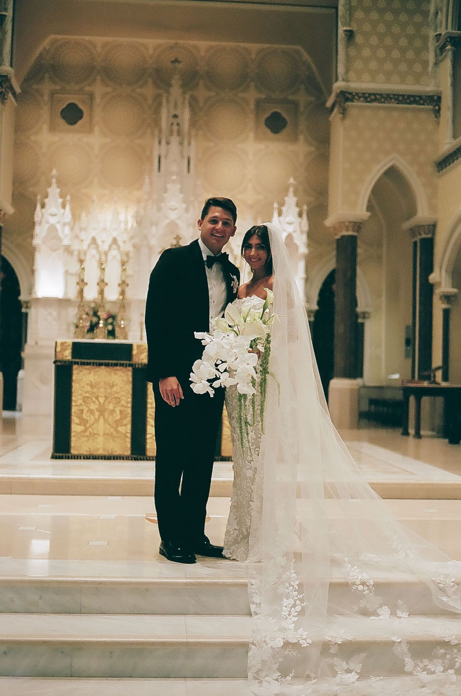 Couple shares romantic moments in an ornate cathedral-style wedding venue with gothic details.