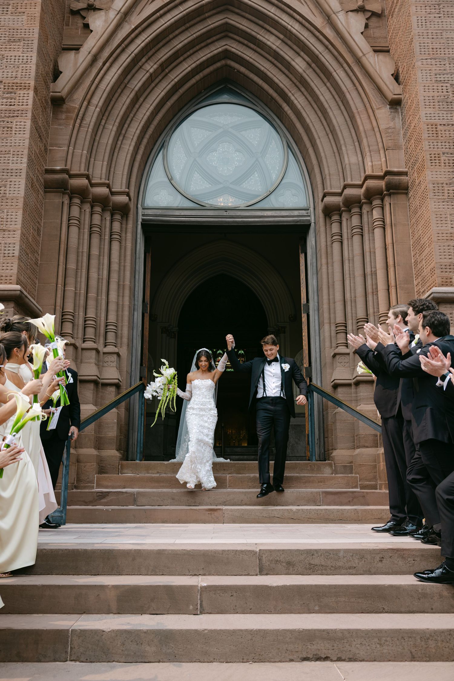 Celebratory moment captured on church steps as wedding party exits ceremony.