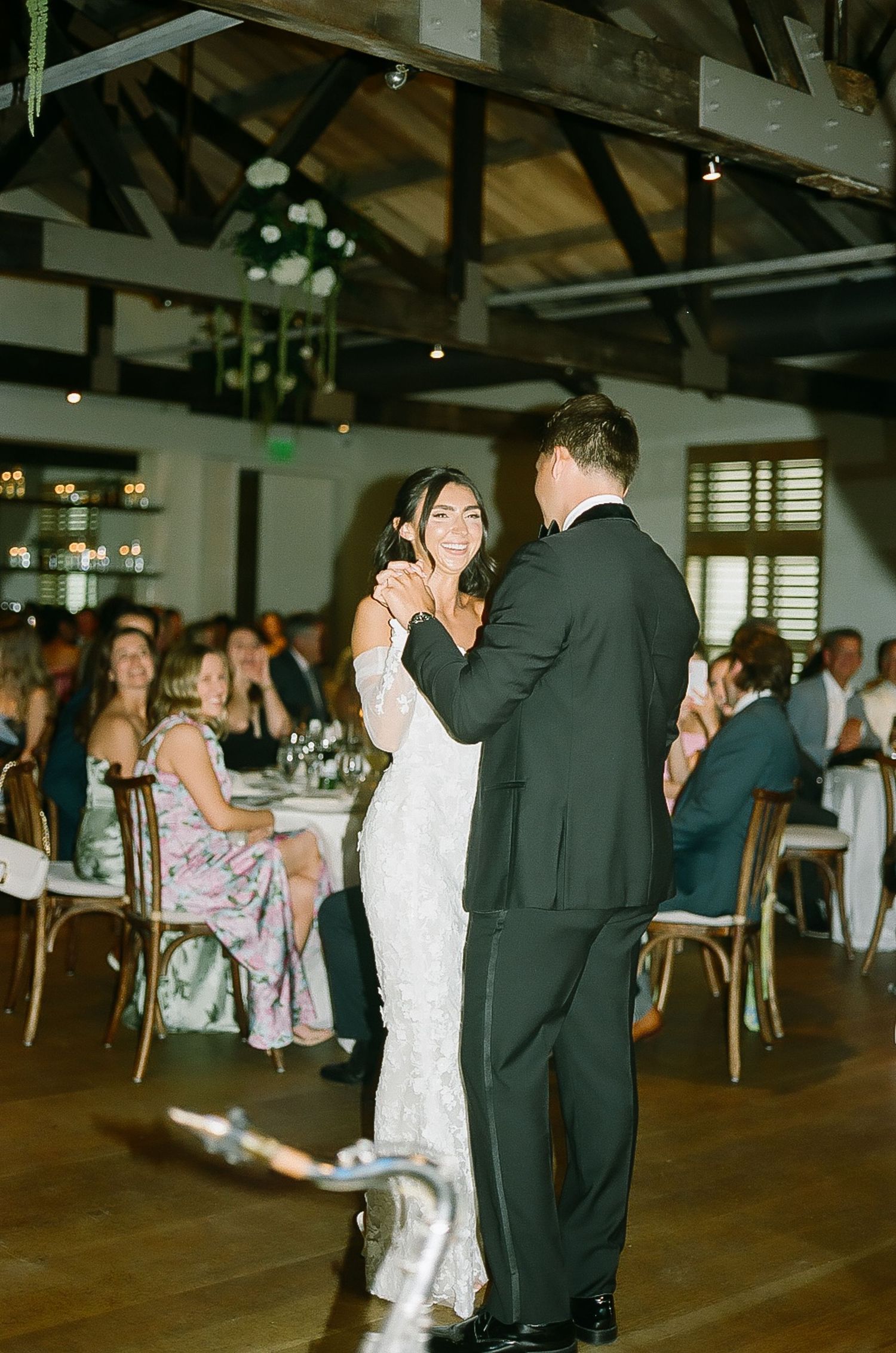 Wedding guests dance and celebrate on a rustic venue dance floor.