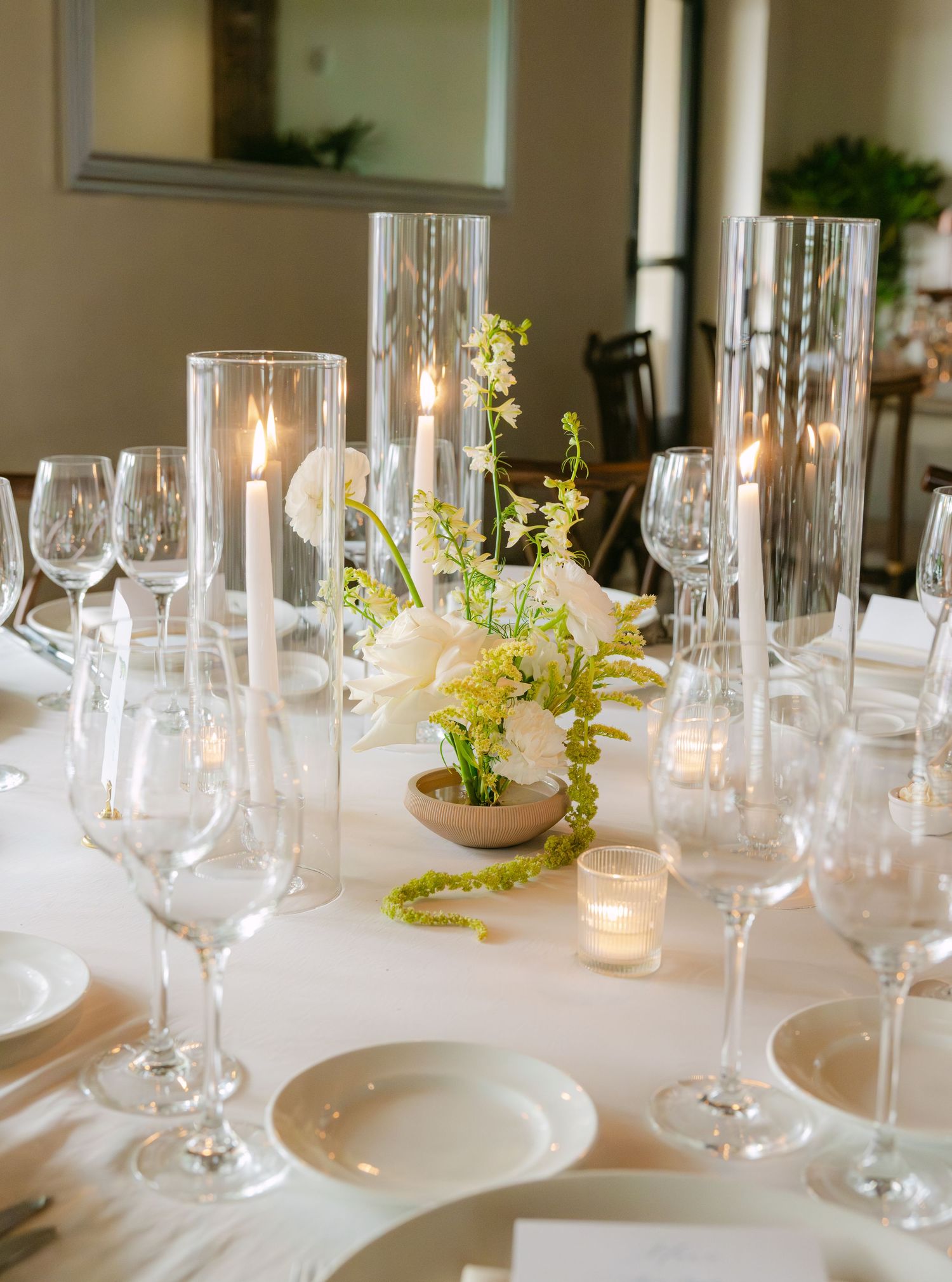 Intimate table setting with stemware, white plates, and candlelight decor.
