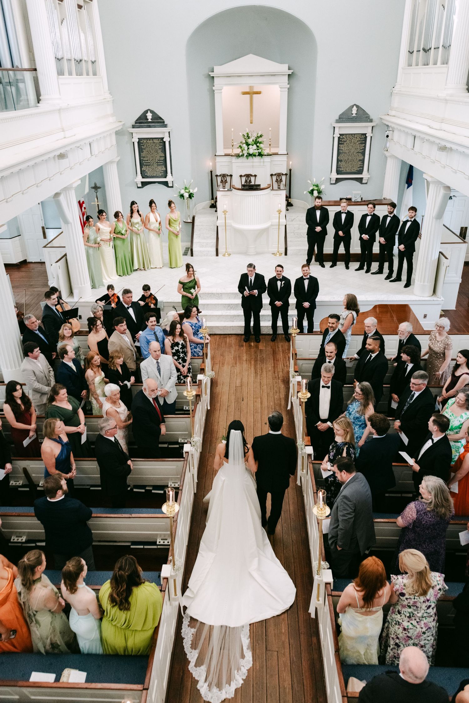Aerial view of a bride walking down the aisle in a classic white church wedding ceremony.