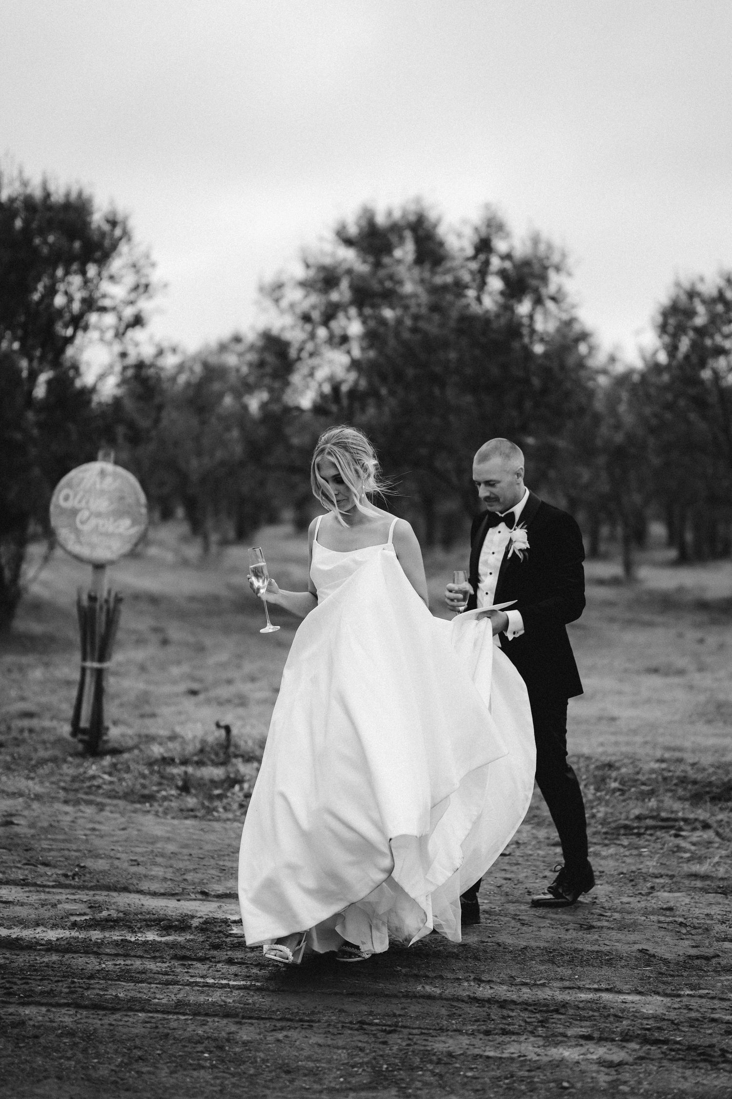 A sequence of black and white photos capturing romantic moments between newlyweds in an outdoor orchard setting.