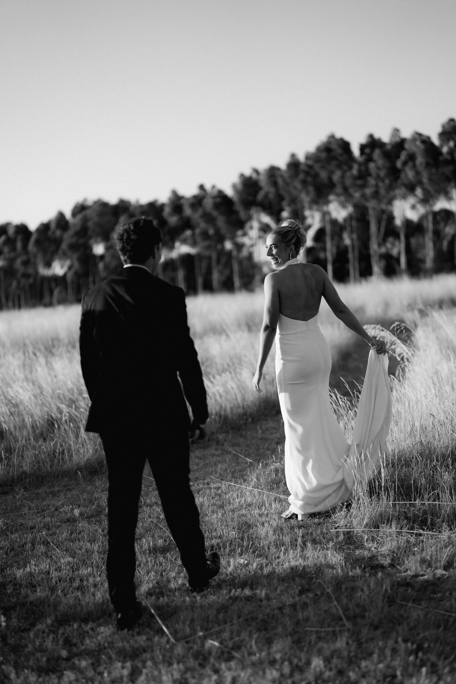 A wedding party walks through a golden field during sunset photography session.