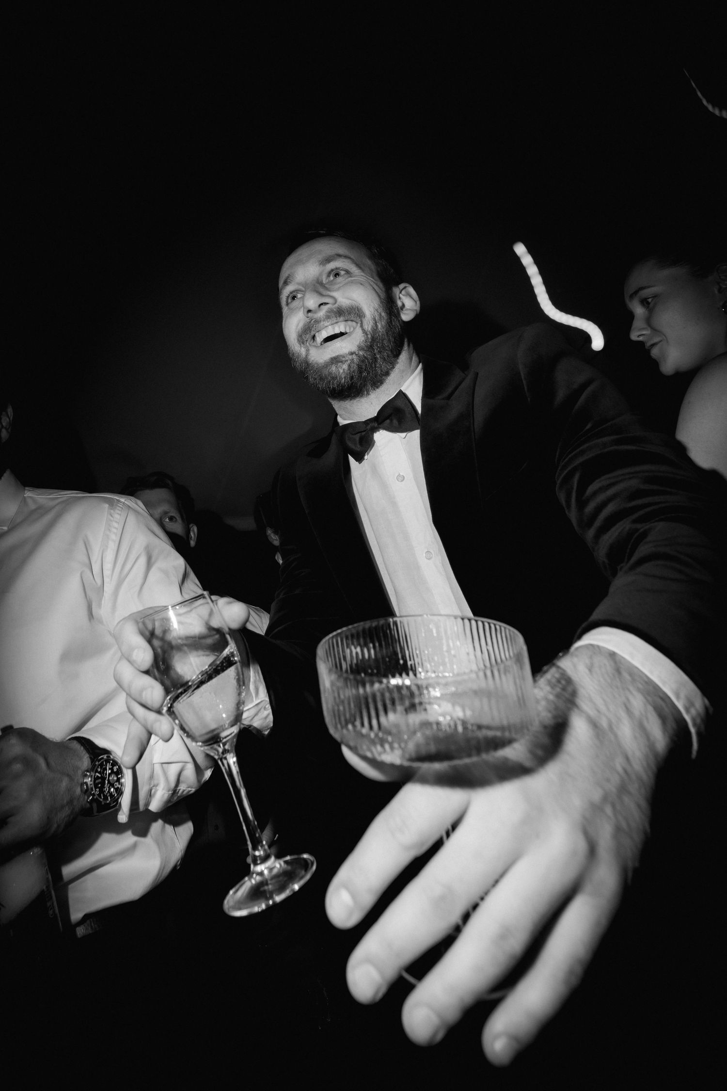 Black and white candid shot of guest enjoying cocktails at reception.