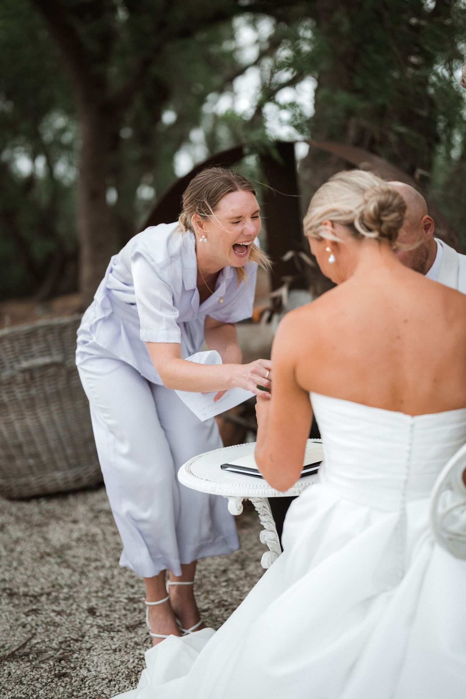 A candid moment of joy and laughter during a wedding celebration outdoors.