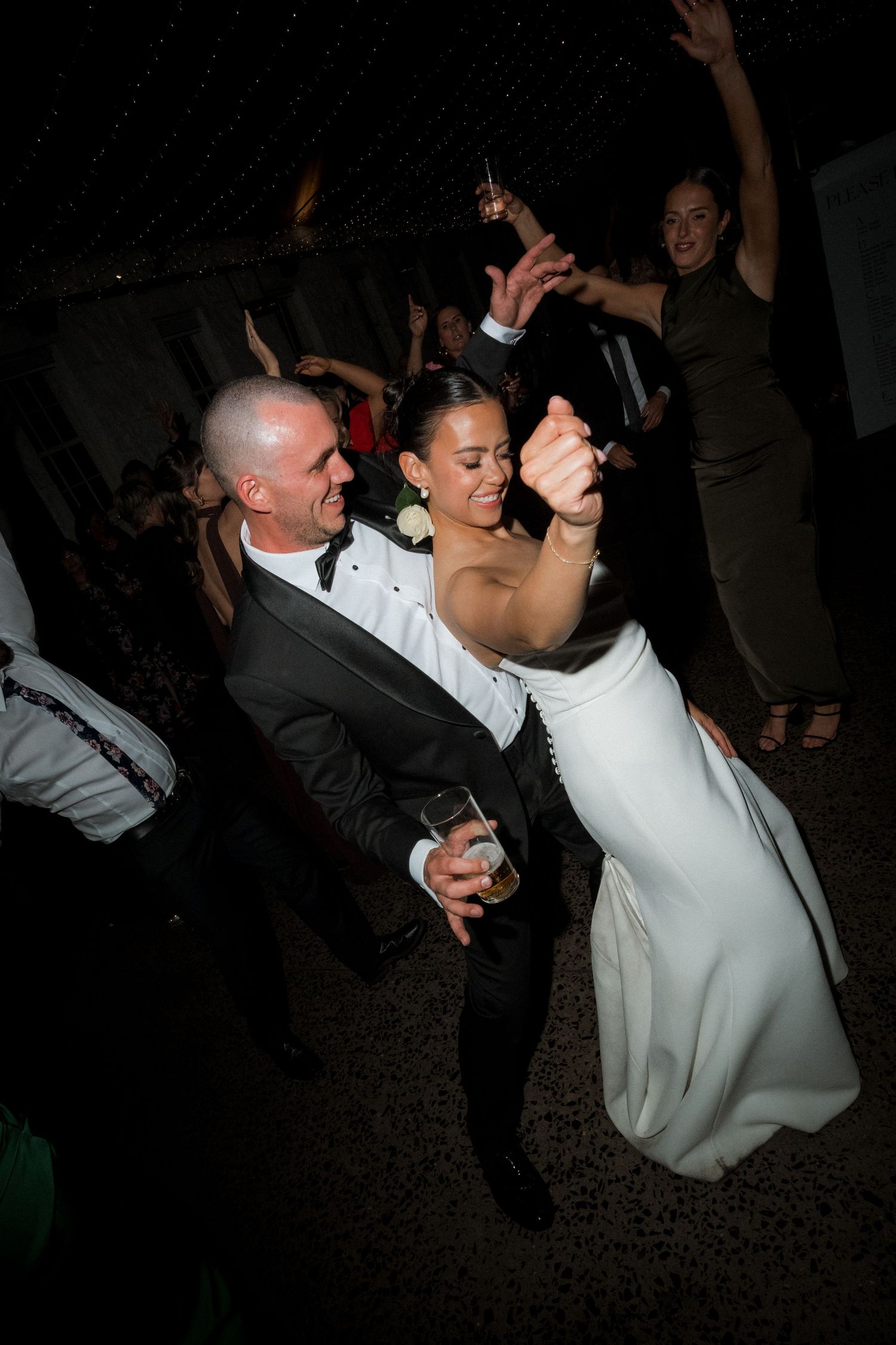 Wedding reception dance floor moments captured in dramatic lighting.
