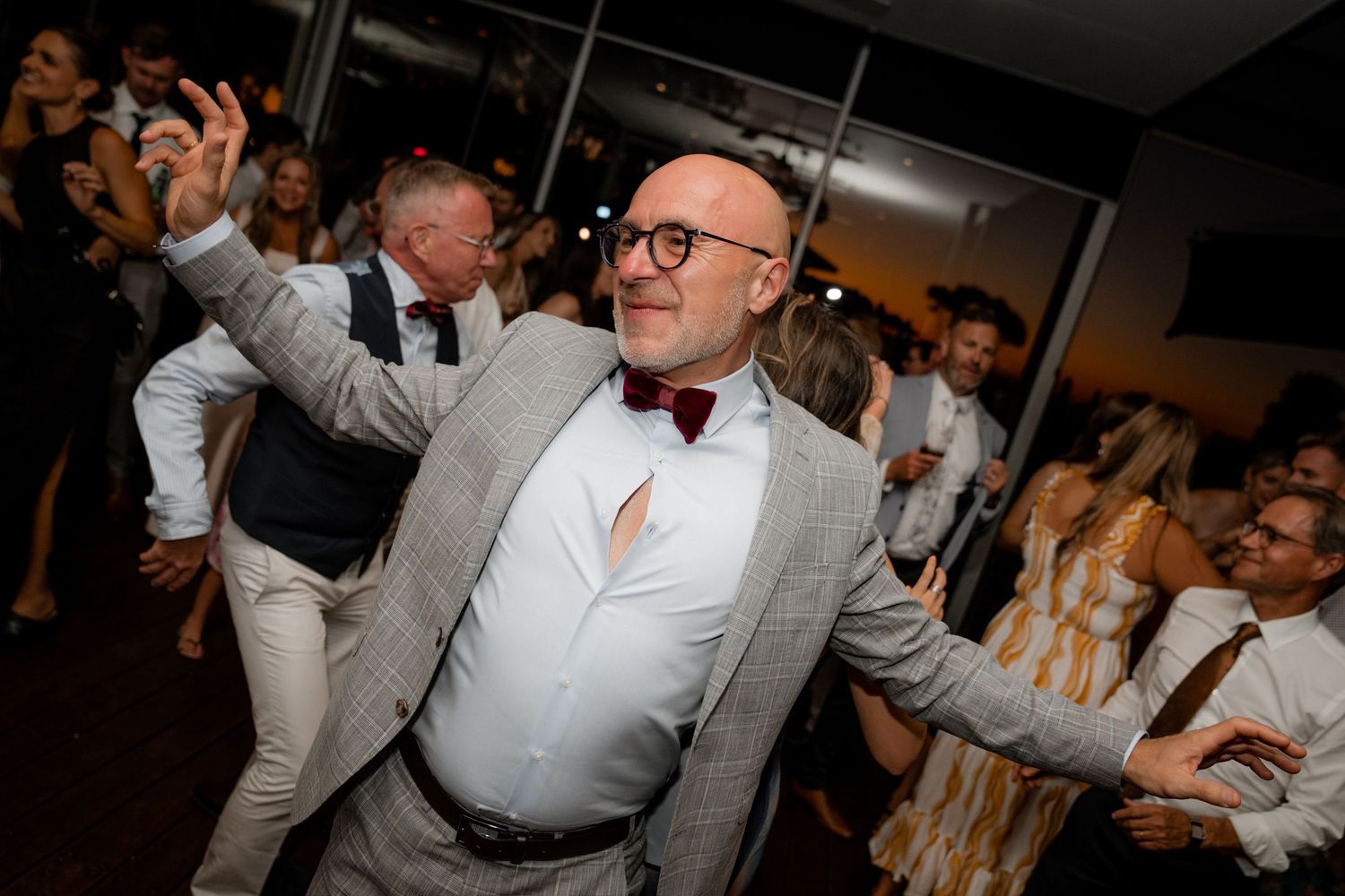 Wedding reception guests dancing and celebrating on a dark dance floor.