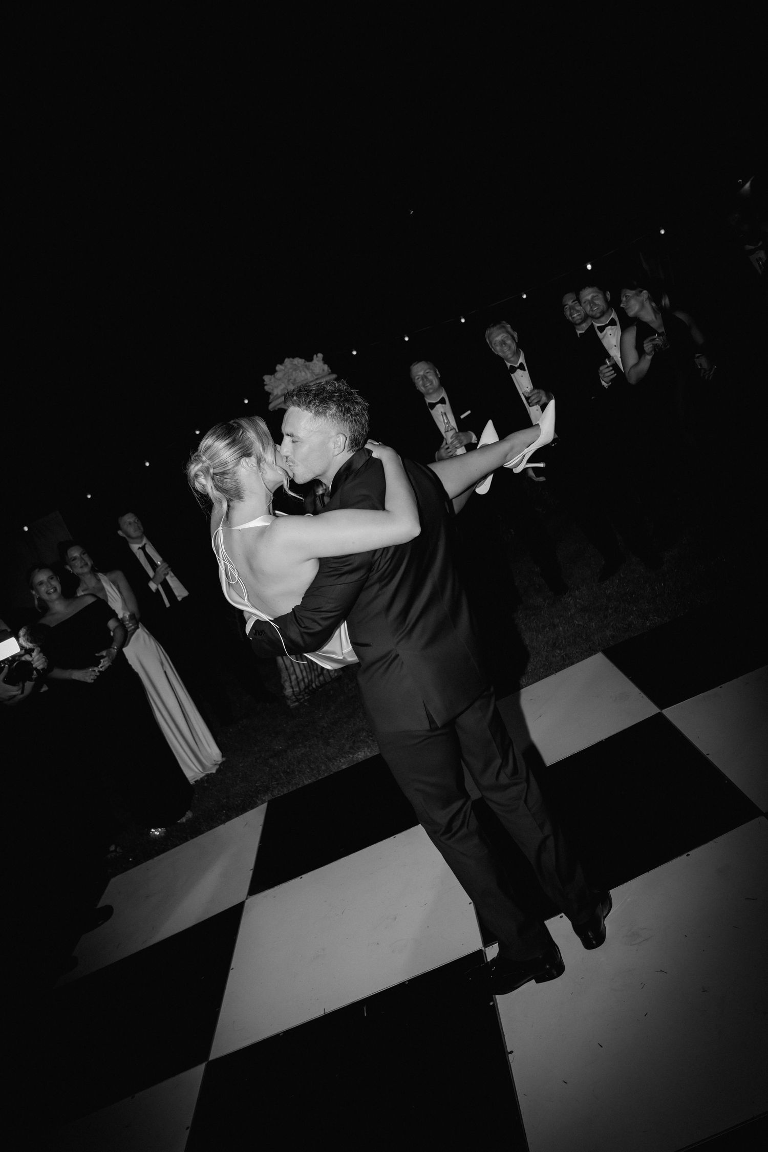 A romantic dance moment captured in black and white on a checkered ballroom floor.